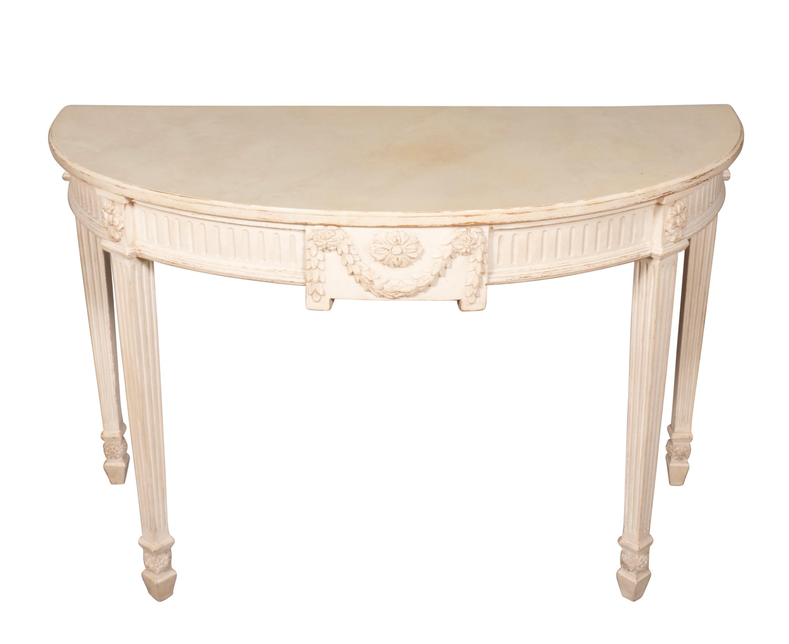 Slightly distressed cream color paint , the demilune shaped tops with conforming fluted frieze and central carved swag and rosette carving. Square tapered fluted legs.