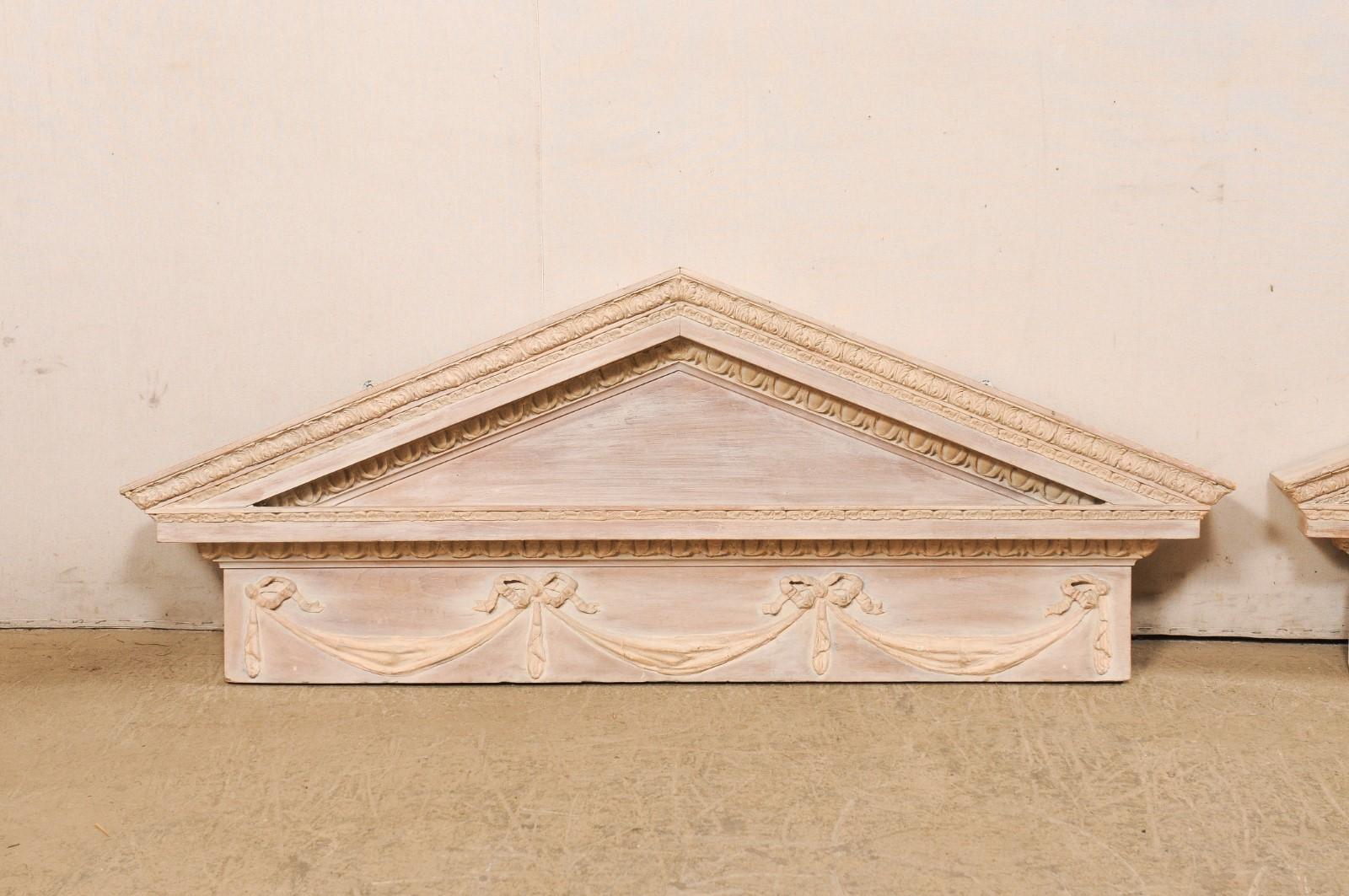 A pair of Neoclassical style carved-wood wall hanging wall pediments, with their original painted finish, from the mid 20th century. These vintage architectural decorations were made in America, but designed with beautiful French Neoclassical