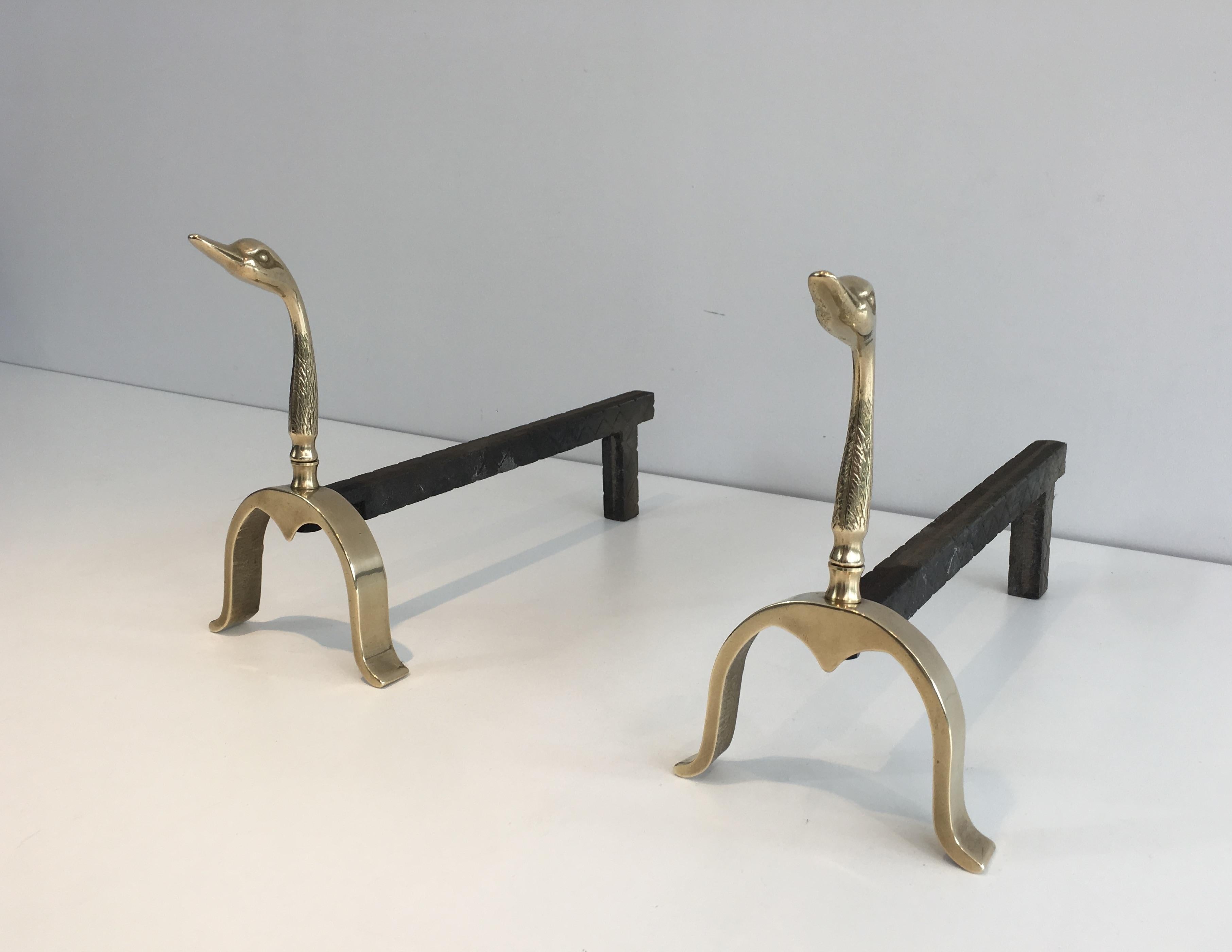 This pair of neoclassical andirons made of brass and iron are displaying duck heads. This is a French work, in the style of Maison Jansen, circa 1960.