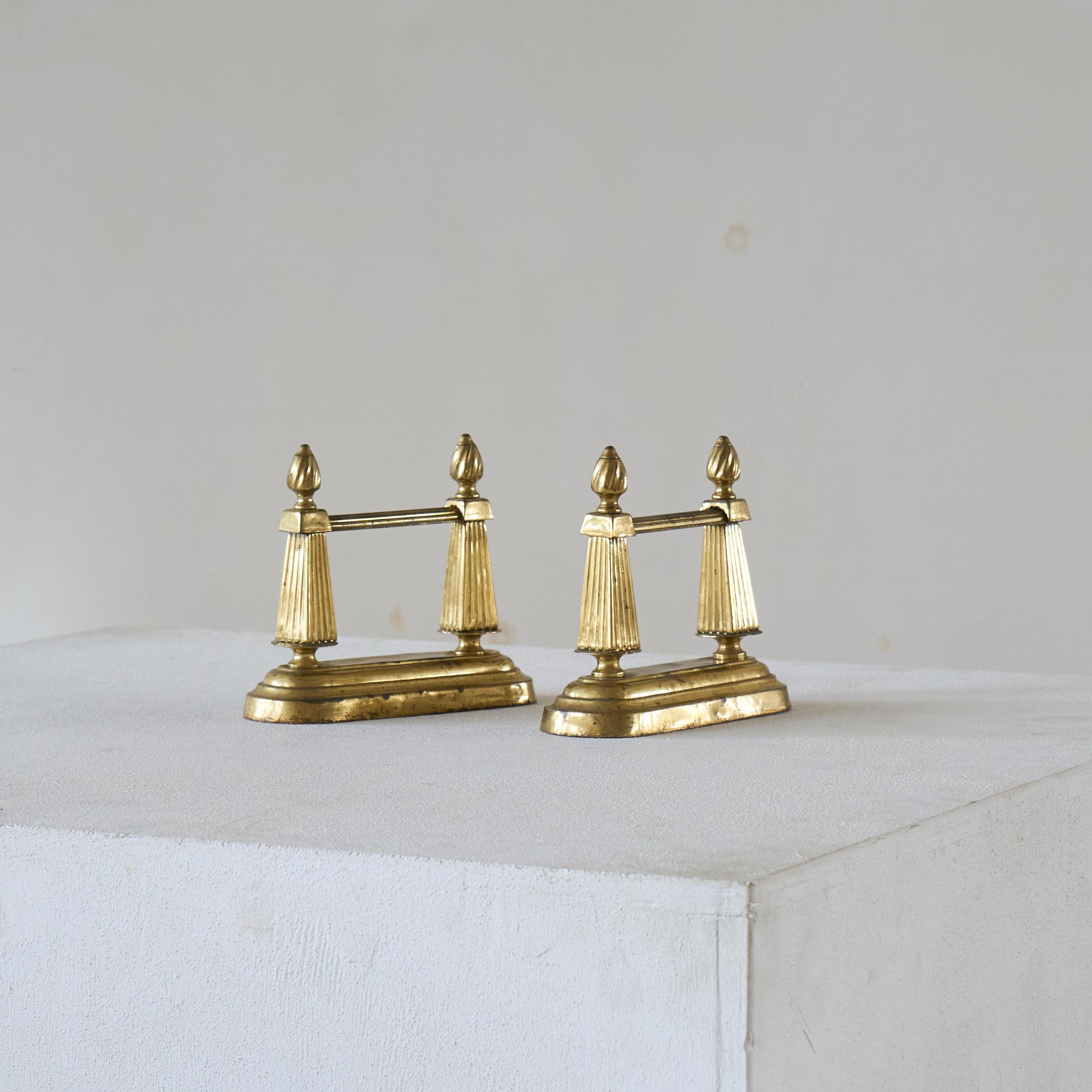 Pair of Neoclassical Andirons in Patinated Brass. Europe, late 19th century.

A wonderful pair of neoclassical andirons or fire dogs of smaller scale. Great neoclassical appearance and design with stylized flames on top. Gained a nice and subtle