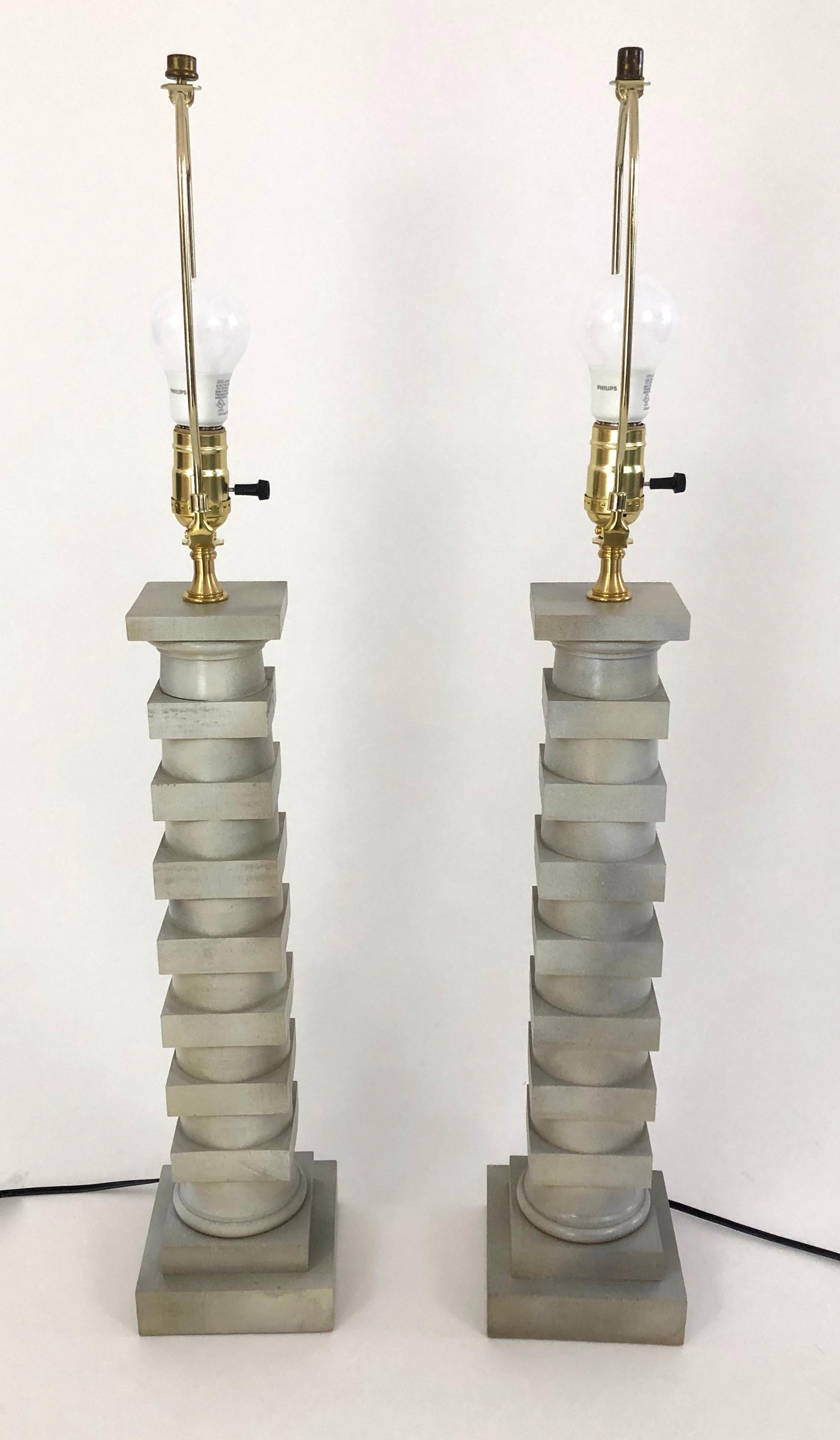 A pair of carved wood lamps in the form of columns, designed by Robert Altman, the cylindrical and stacked square design inspired by the work of French neoclassical architect LeDoux, in a grey faux stone finish. Shades optional.
Dimensions:
Overall