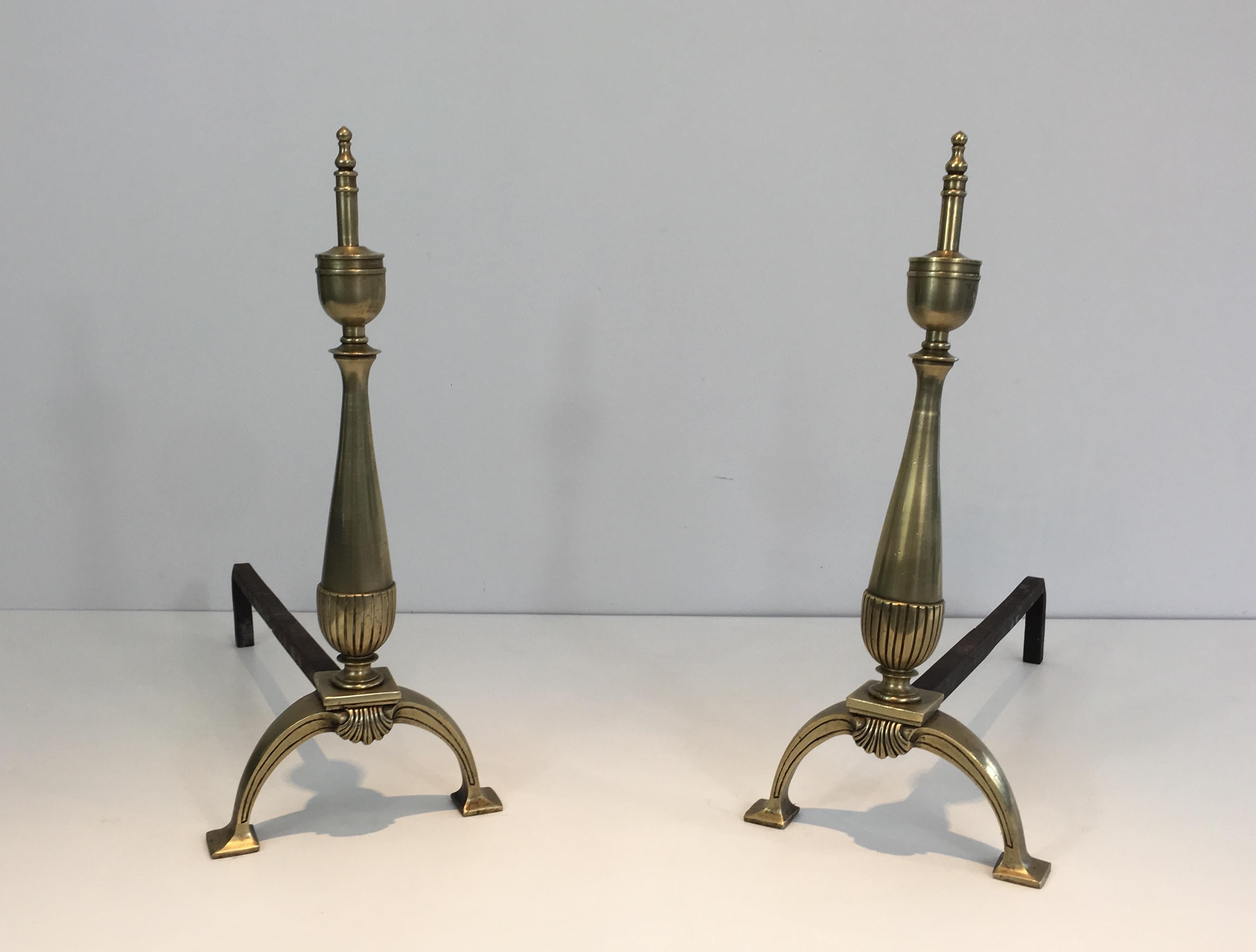 This elegant pair of andirons in the neoclassical style is made of brass and wrought iron. This is a French work. Circa 1940.