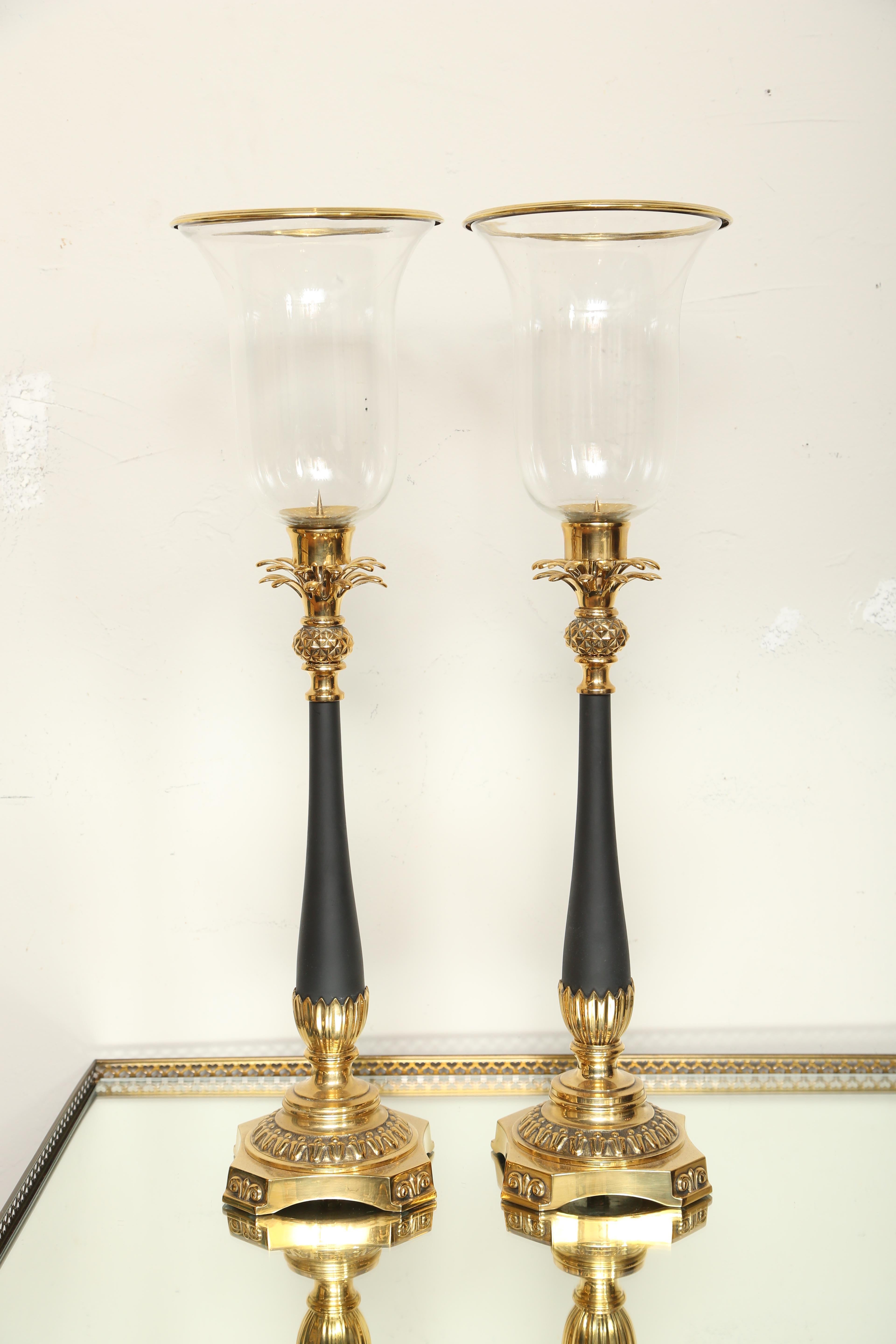 Pair of brass and black bisque pineapple hurricanes. Removable brass rim on top of glass.