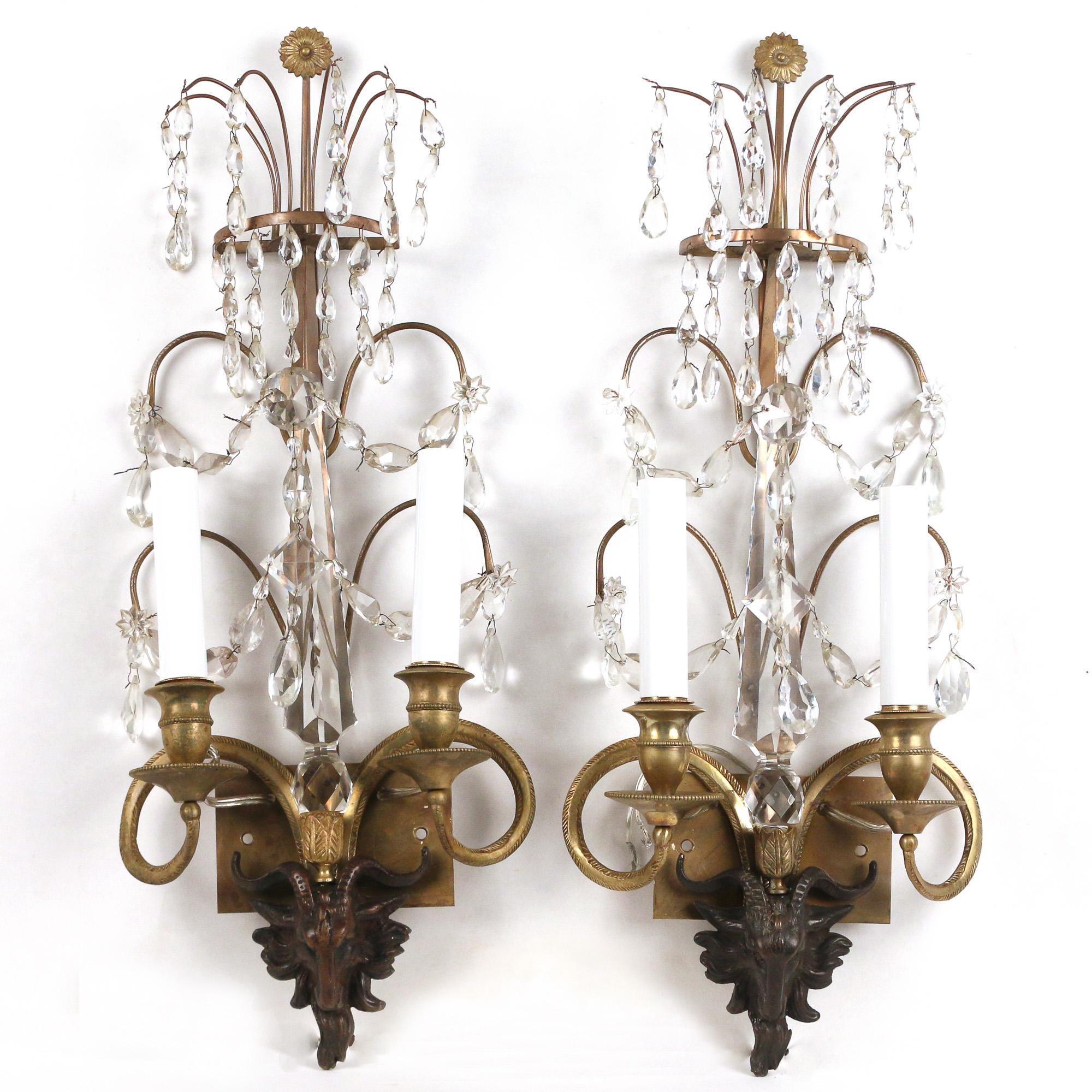 Fine pair of early 19th century patinated and gilt bronze and crystal wall lights, having flower head finial over a series of branches with drops and two tiers of swag draped arms, having a single cut spier over chocolate brown patinated goat's head