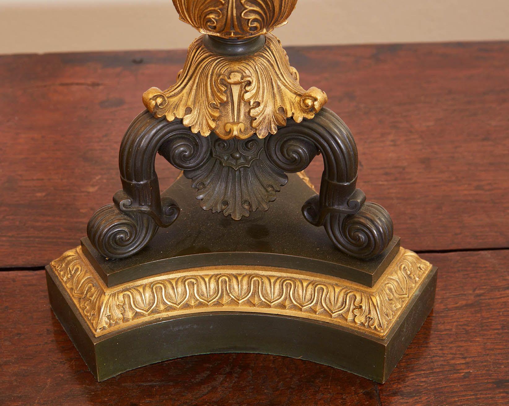 Paire de lampes de table à colonne en bronze de style néoclassique. Chaque lampe possède une colonne centrale cannelée en bronze patiné avec un chapiteau et une base en bronze doré et élaboré, reposant sur une base concave en trèfle avec trois pieds