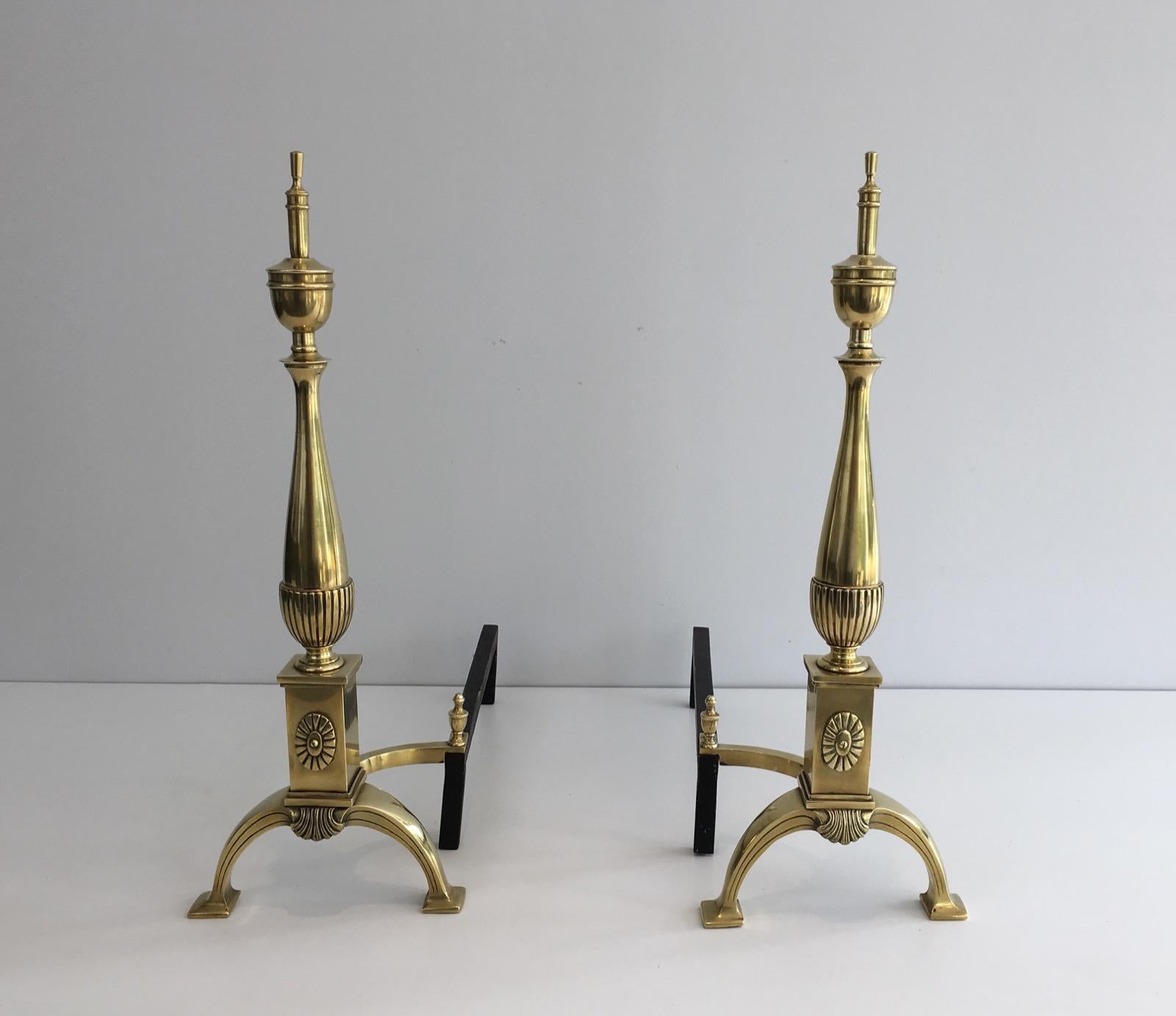 This pair of andirons in the neoclassical style are made of brass and wrought Iron. They are French, circa 1940.