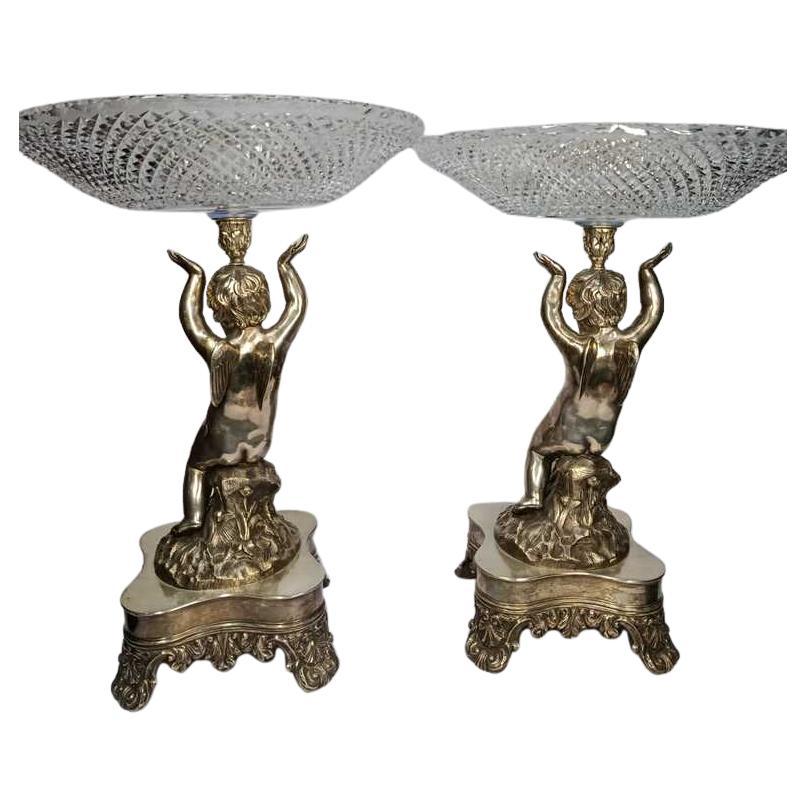 Pareja de centros de mesa neoclásicos con querubines, 1900, Inglaterra

Descripción:
Magnífico par de centros de mesa de origen inglés, realizados hacia 1900 en estilo neoclásico. Cada pieza está finamente elaborada en bronce plateado y cristal, y