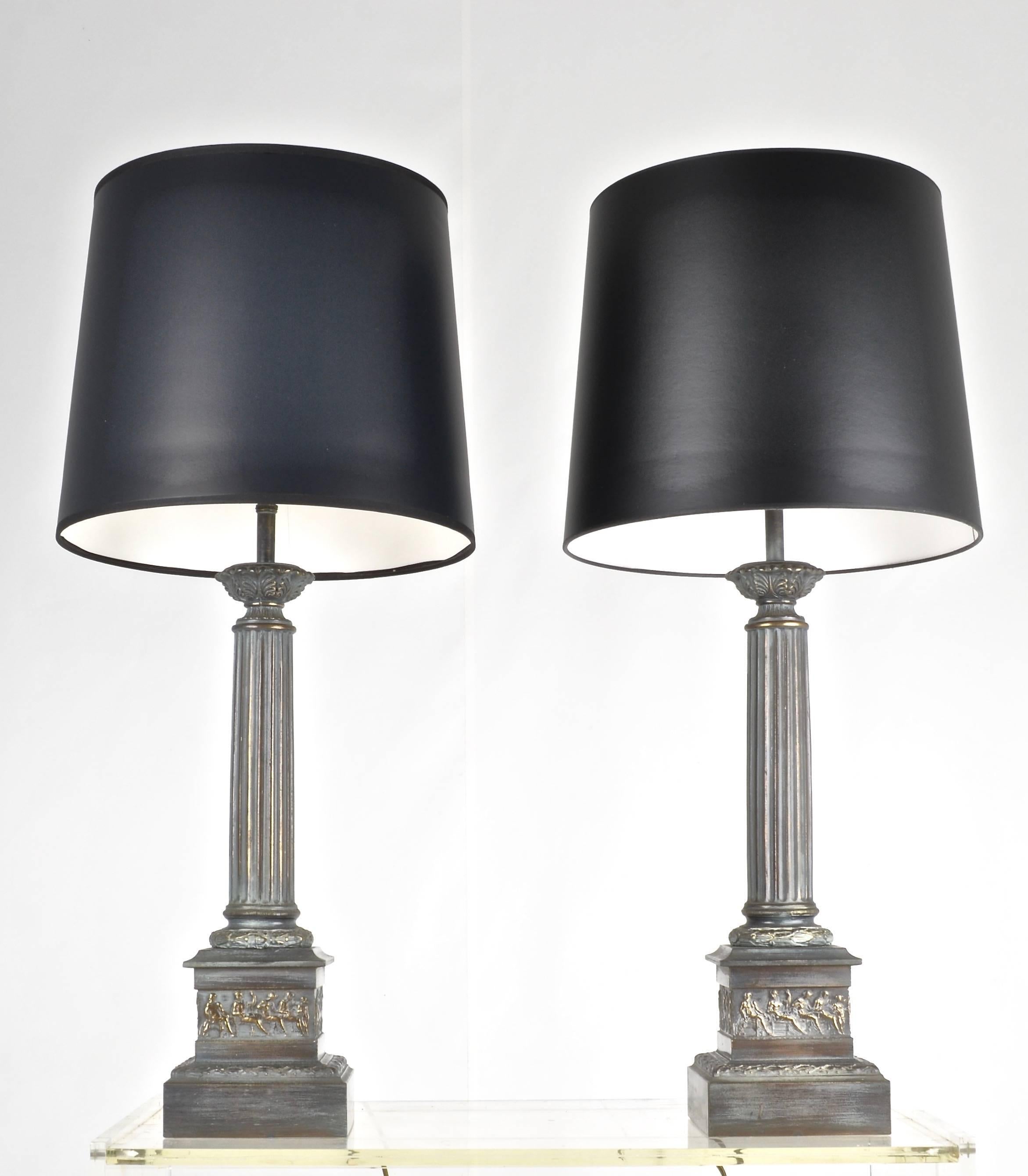 A handsome pair of metal lamps, featuring a neoclassical motif in a verdigris bronze finish. All new wiring and three-way sockets in bronze tone. New shades opaque black paper. Height to the top of the socket is 24.5 inches; to the top of the finial