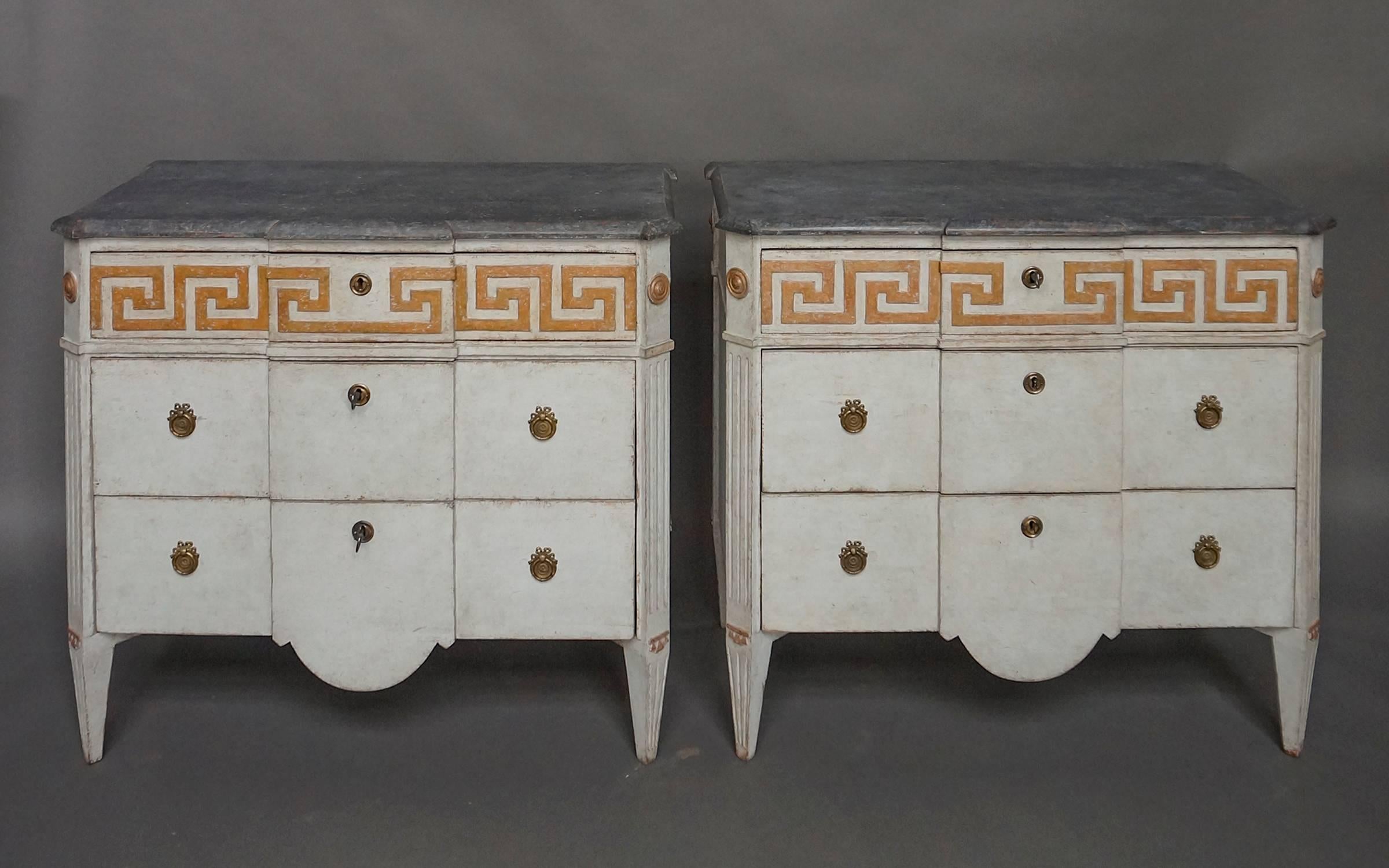 Pair of Swedish commodes, circa 1880, with paneled facade, the top drawers having raised Greek key molding. Shaped top and canted corners with rondels above reeded corner posts and tapered legs. The boldly curved aprons on the bottom drawers add to