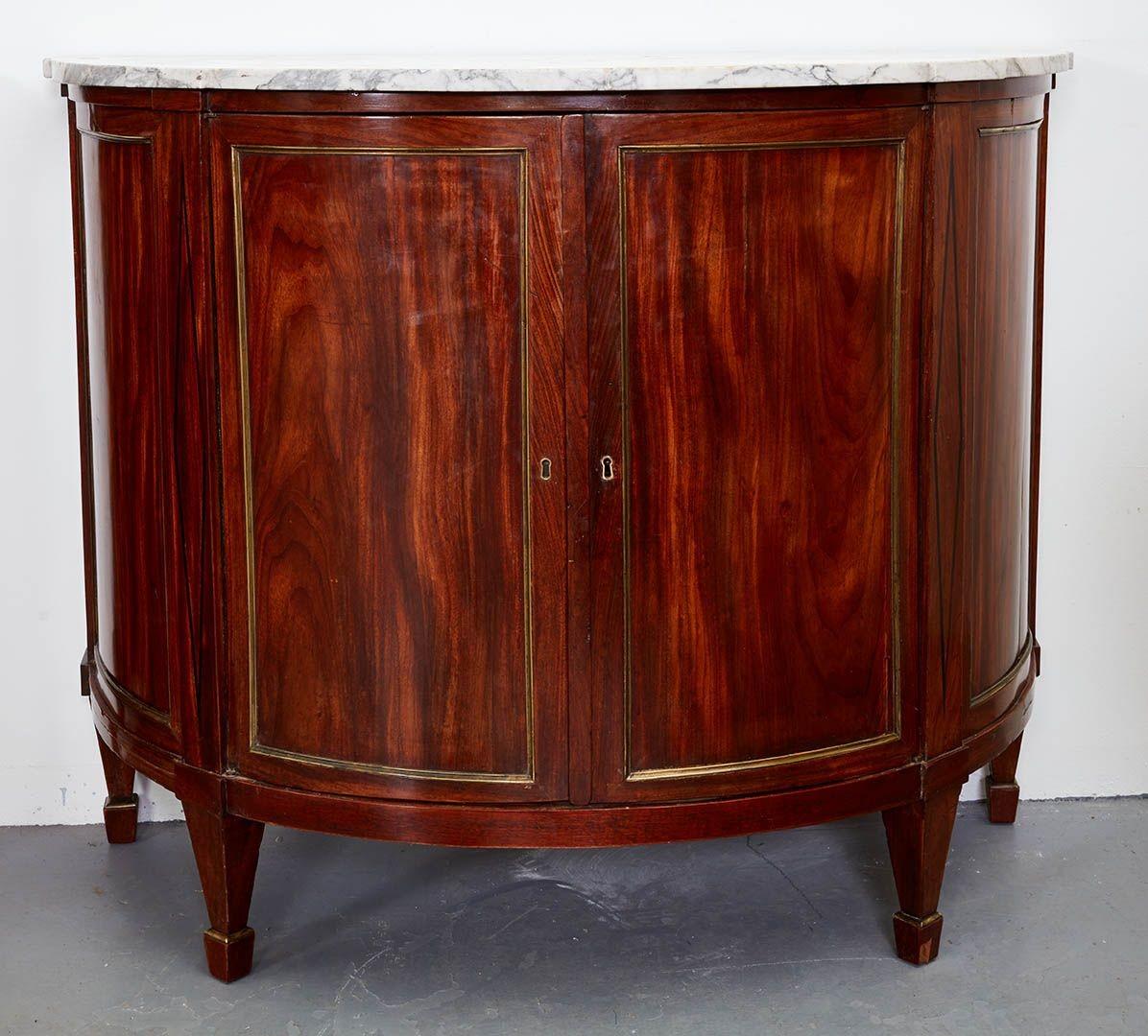 A very fine pair of early 19th Century Northern European neoclassical demilune commodes, the original shaped marble tops over two brass molded doors, the cabinet interior with one drawer and one shelf, the pilasters with ebony diamond inlay and