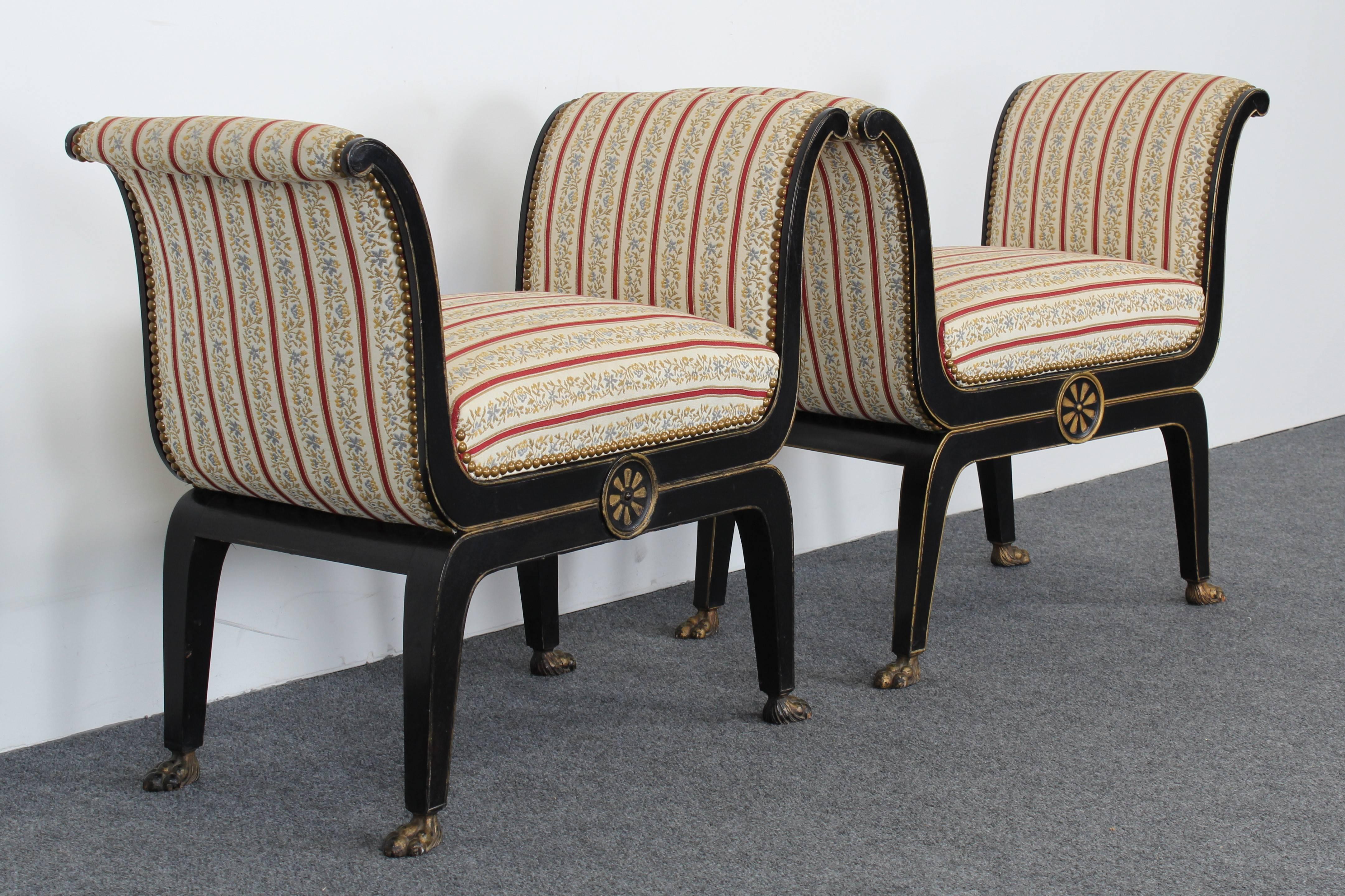 An elegant pair of neoclassical Directoire Regency style ebony and gilt benches with paw feet and decorative motif. Structurally sound with age appropriate wear. Some staining to fabric, new upholstery recommended.