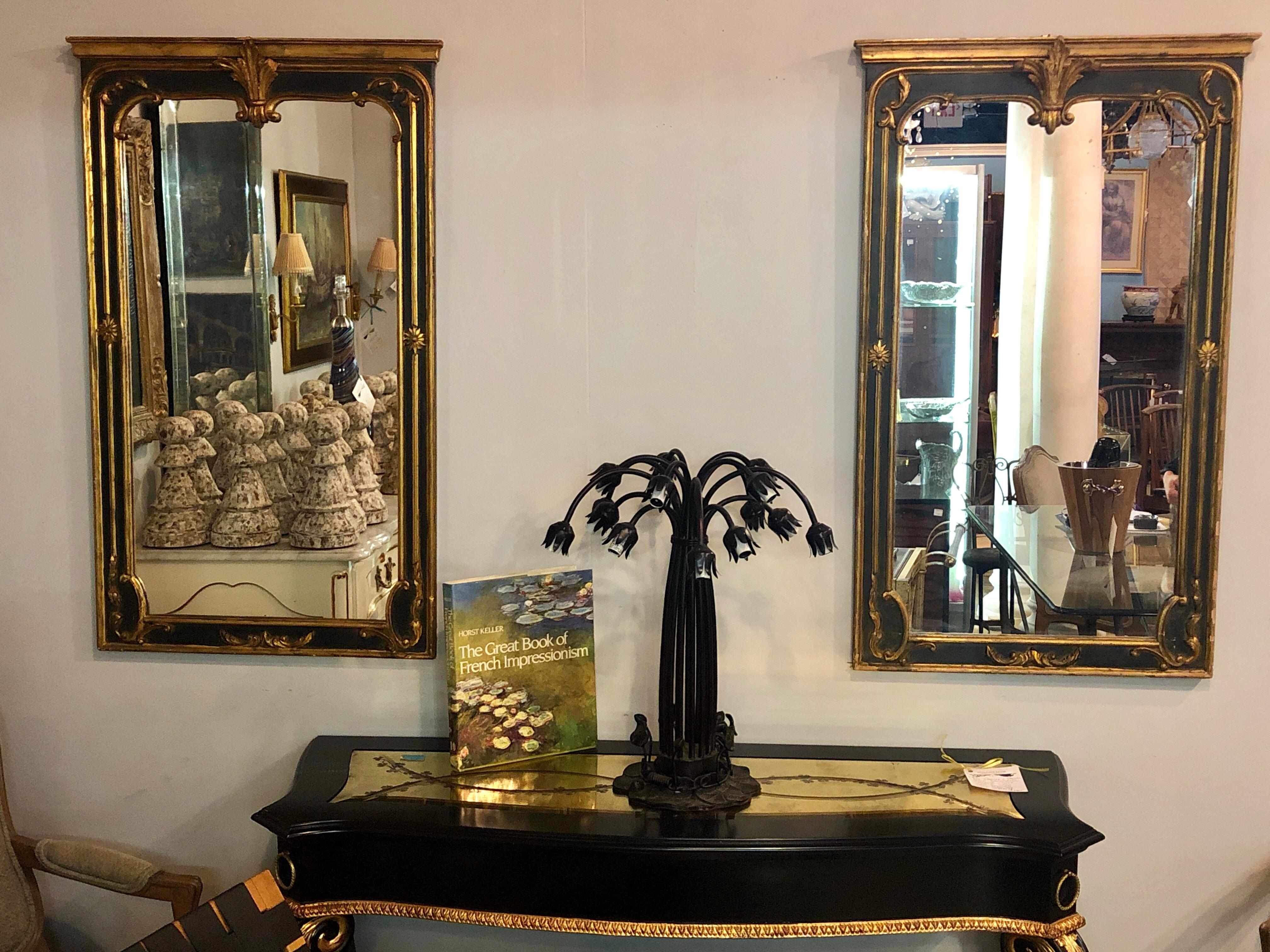 Pair of Neoclassical Italian ebony and gilt decorated / wall / pier or console mirrors in the Maison Jansen fashion. Each having an ebonized and parcel gilt finish. This Mid-Century Modern pair with carved shell crested tops and carved sides and