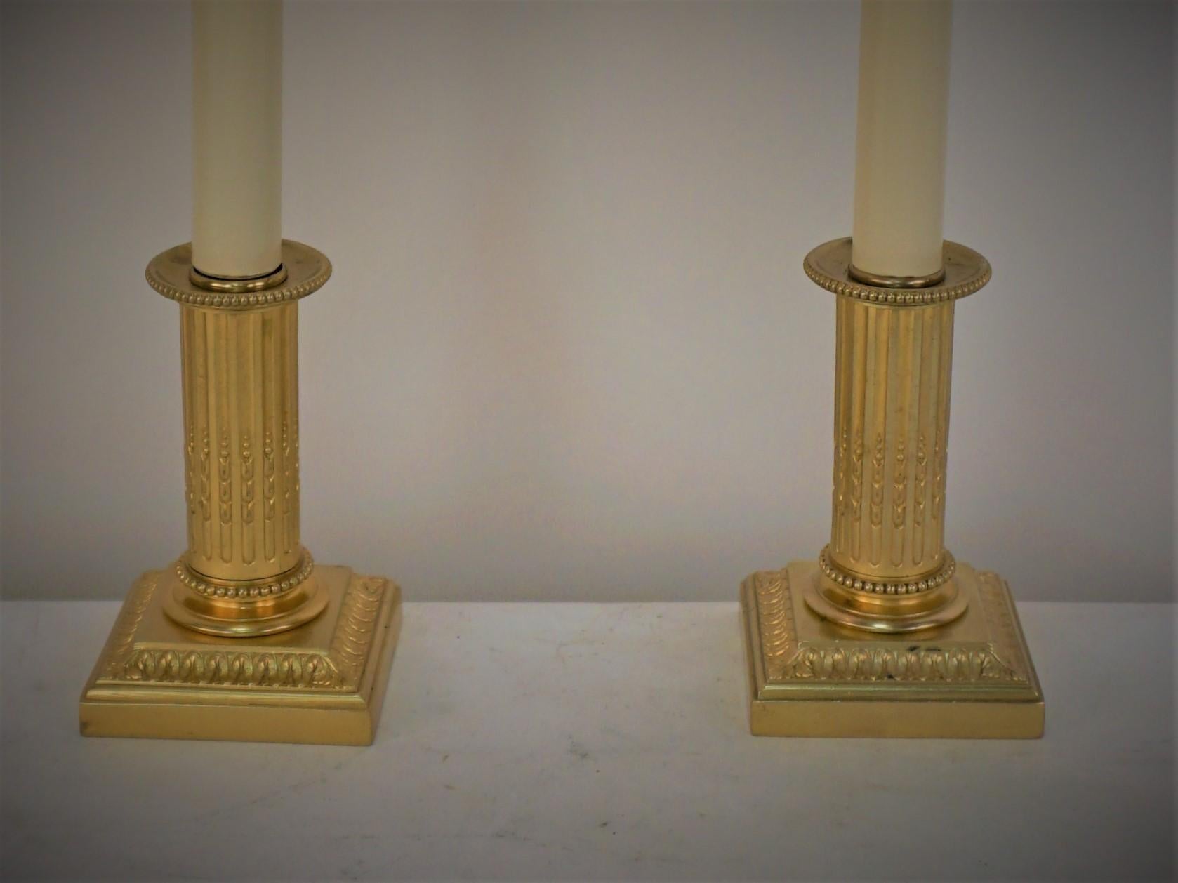 Pair of classic design bronze candlestick that have been electrified as table lamps. 
Measurement includes the lampshade.