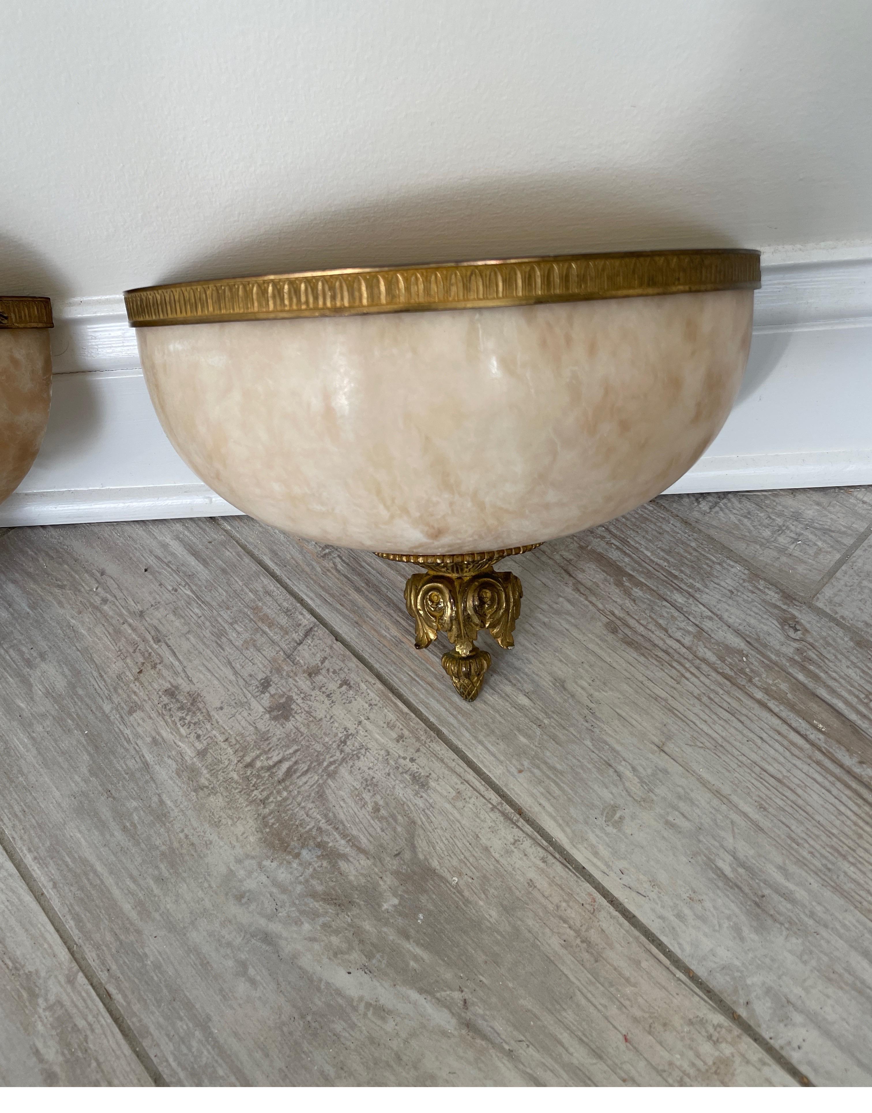 Pair of French neoclassical Alabaster and bronze wall mounted lights. These Parisian sconces will look great in so many settings. They are demilune shaped with bronze trim on top & an acorn finial on bottom.