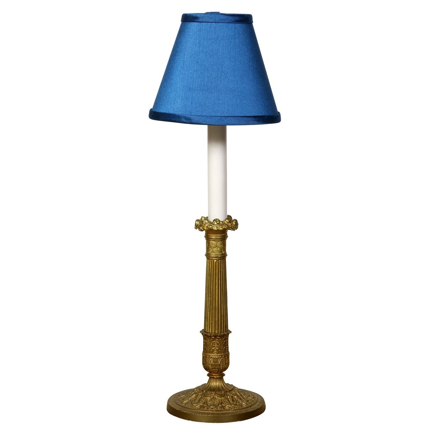 Un par de lámparas candelabro neoclásicas de latón dorado. Estos portavelas de latón dorado se han transformado expertamente en lámparas de mesa electrificadas, combinando la elegancia clásica con la funcionalidad moderna. Fabricadas en estilo