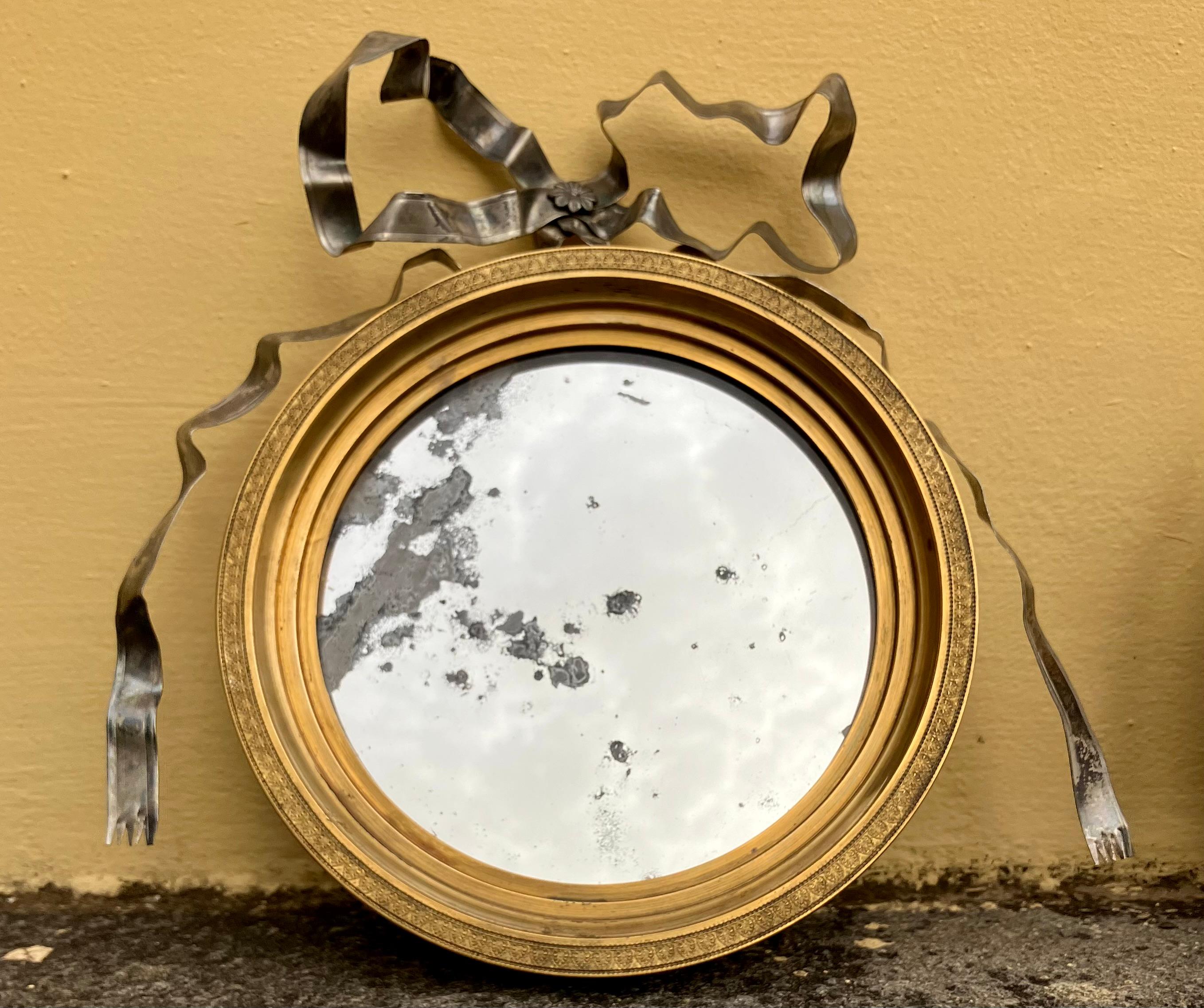 Coppia di specchi neoclassici in bronzo dorato e argento a nastro.  Coppia di specchiere tonde Luigi XVI dell'Impero graduate in ormolu con bordo in acanto e perline che racchiudono una lastra originale in vetro di mercurio sormontata da fiocchi in