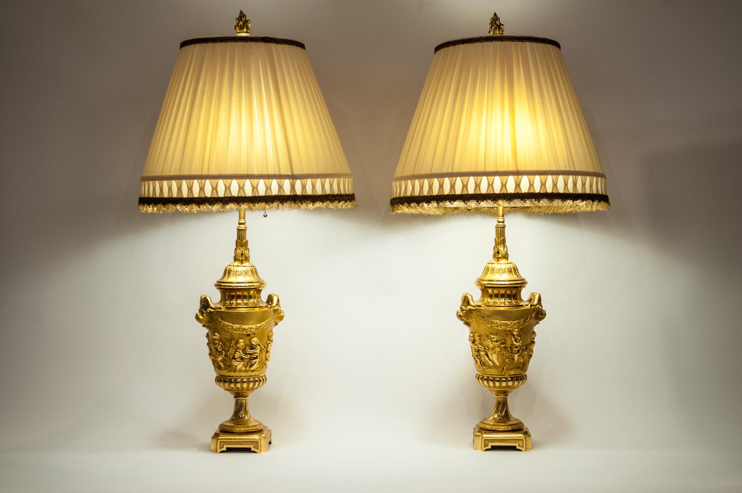 A pair of neoclassical gilt bronze urn-form task / table lamps. Each lamp is in excellent working condition. Each lamp comes with a silk pleated bell shape shade . Each lamp measure about 28 inches high and 33 inches to the top of the fenial X 8