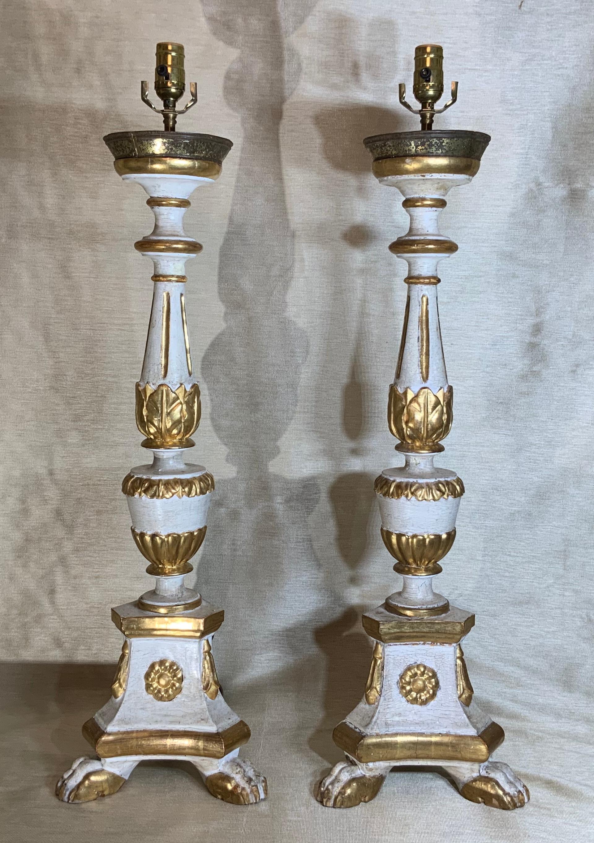 Pair of vintage Italian neoclassical style carved gold giltwood candlesticks converted to beautiful table lamps, features white cream gesso and gold gilt polychrome finish, solid carved wood, two front paw feet and one support in the back. Round top