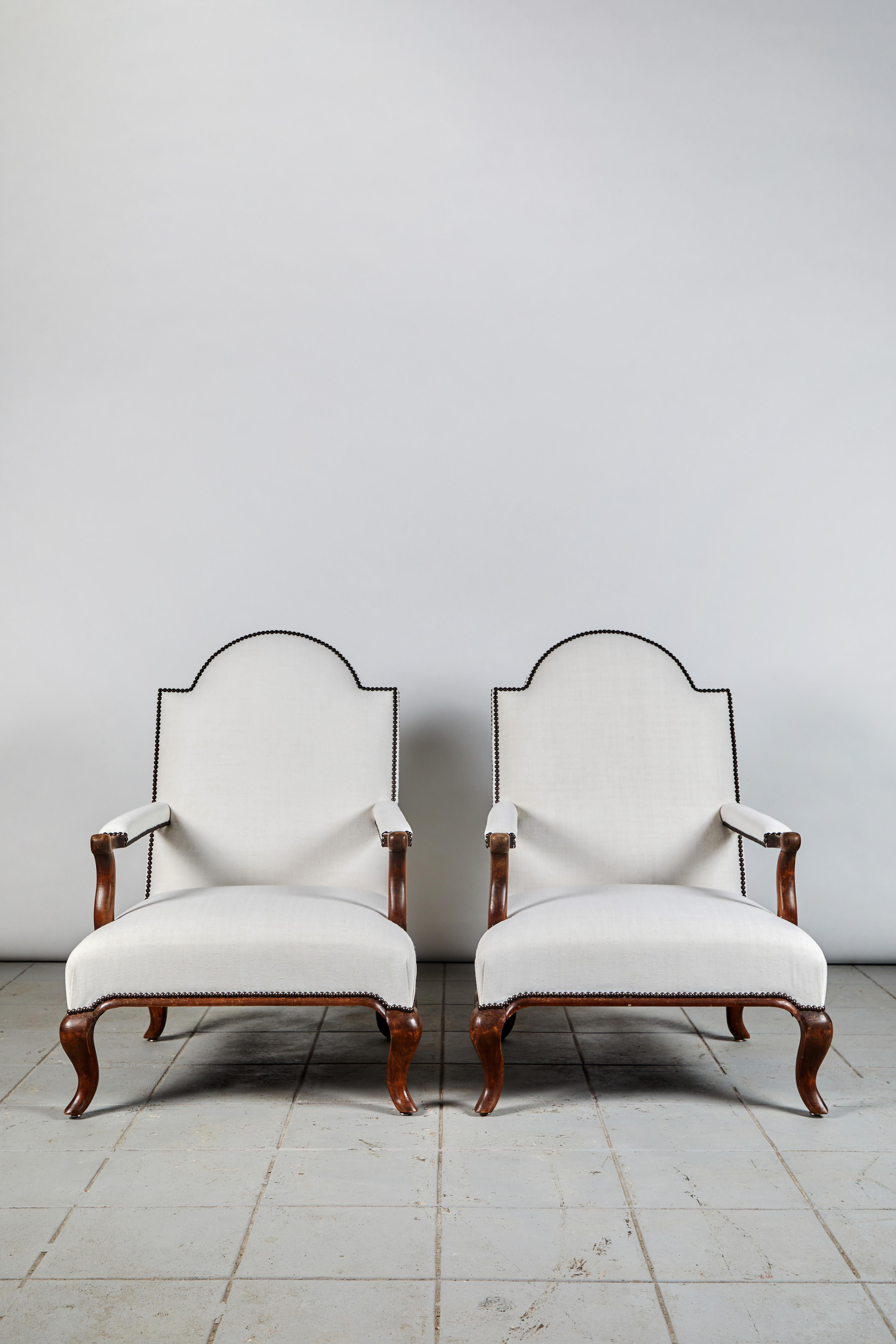 Pair of neoclassical Italian chairs upholstered in Belgian linen with new nail heads. The armchairs have a beautiful original stain to the wood.