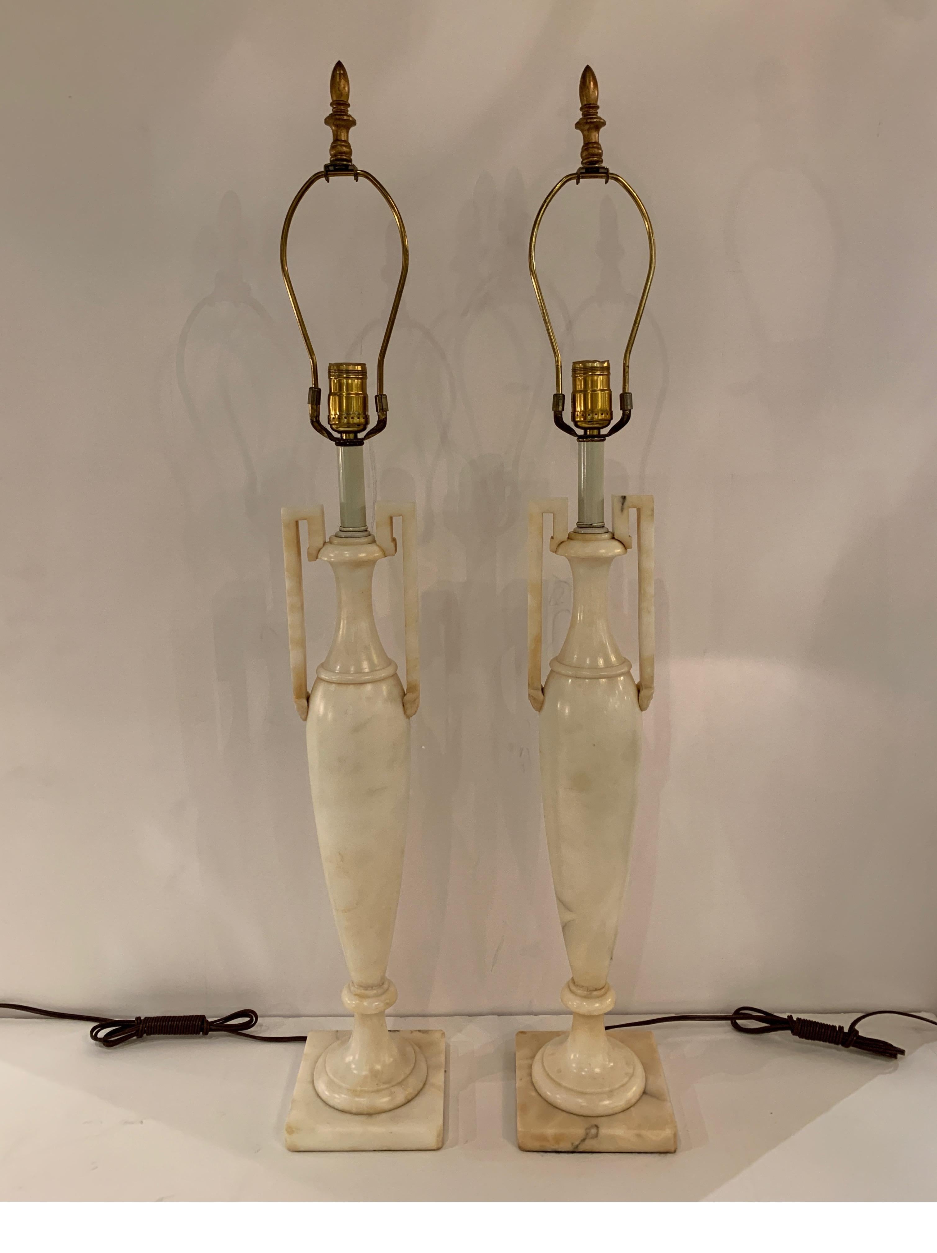 Chic pair of neoclassical marble urn lamps. The stylish elongated shape with a Greek style handle on each side. The shades are for photographic purposes only and not included with the lamps. Measurement without shade to the top of the lamp, 27