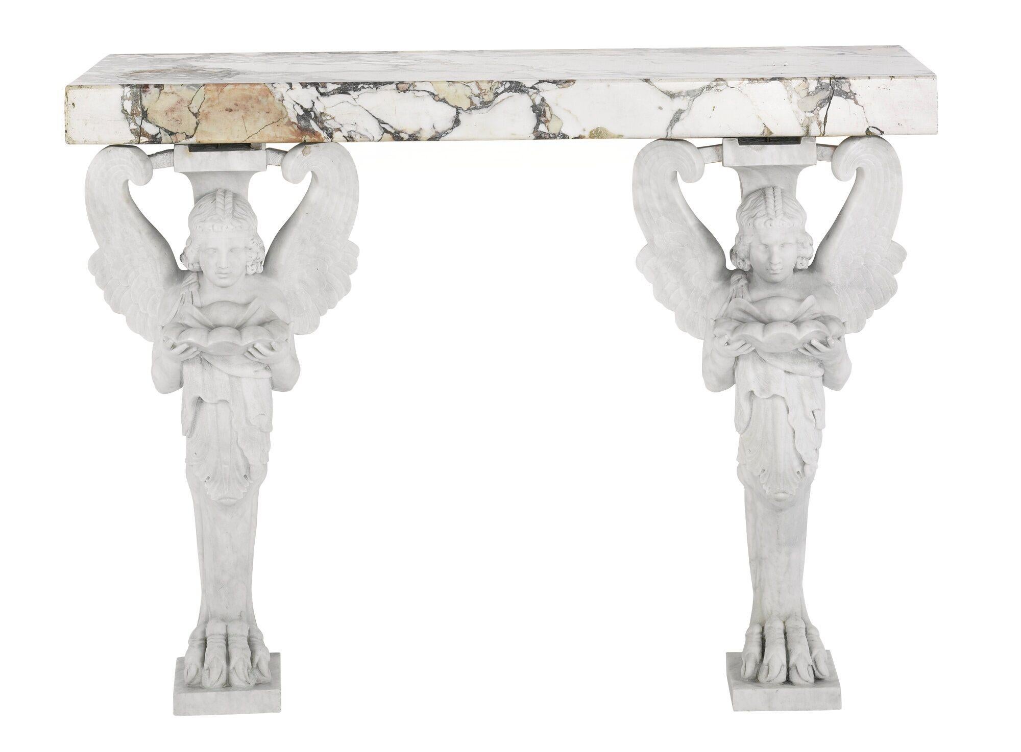 Pair of 20th century carved marble and breche violettte marble topped console tables. Each with a winged figure holding a votive shell. Wall mounted

Provenance: Sotheby's Private Collections Sale, April 2015.