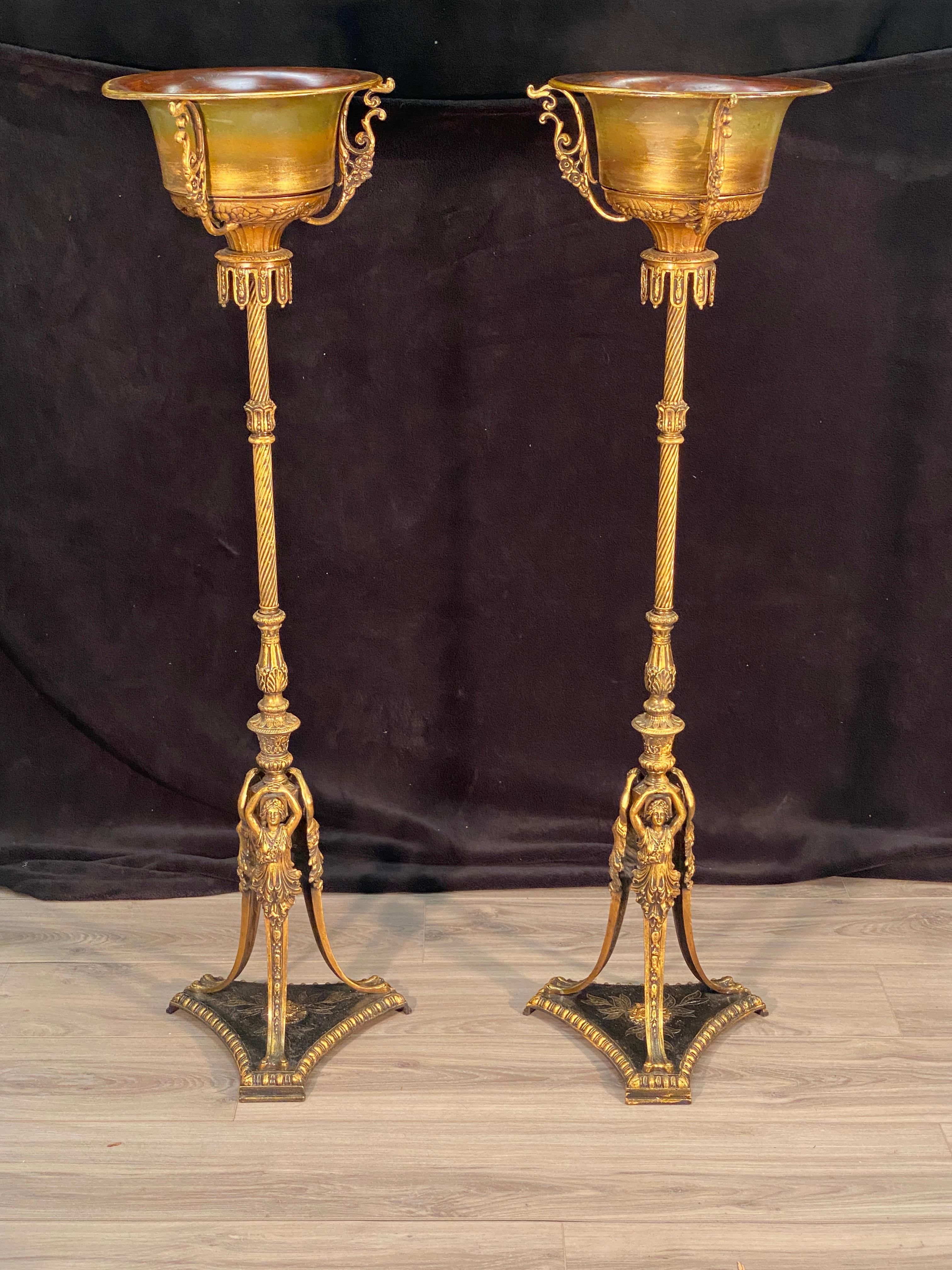 Pair of Neoclassical plant stands. Three foot female effigy applied with an accent base. The top copper bowls are removable. Thy main post is a turned column with acanthus detail. 

Measures: 48