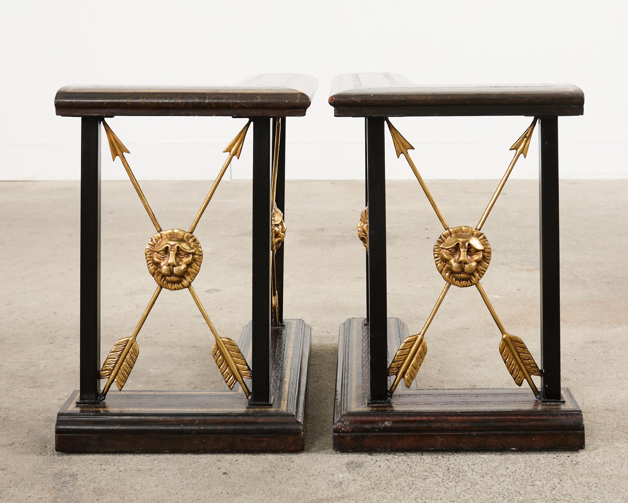 Impressive pair of fireplace fender bench seats made in the English regency taste by Maitland-Smith. The bench seats feature neoclassical style x-form patinated brass arrows centered by lions head medallions. The tops of the fenders have a tooled