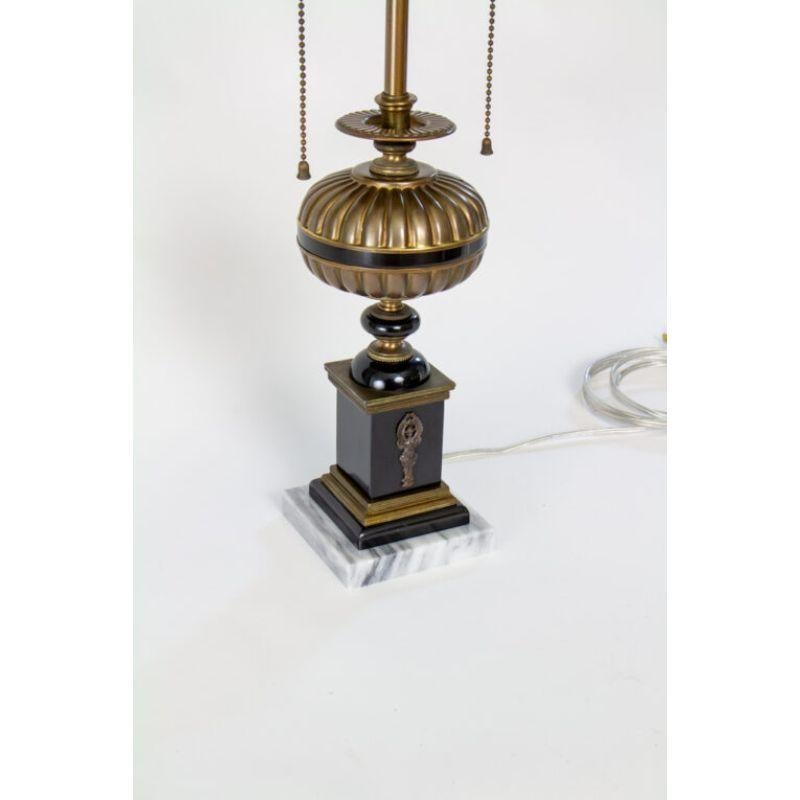 Pair of brass and black table lamps with marble bases. A winged figure adorns the front and back on the base. Brass has original patina, cleaned and wax polished. Resin has been cleaned and polished to it’s original shine. Completely restored and