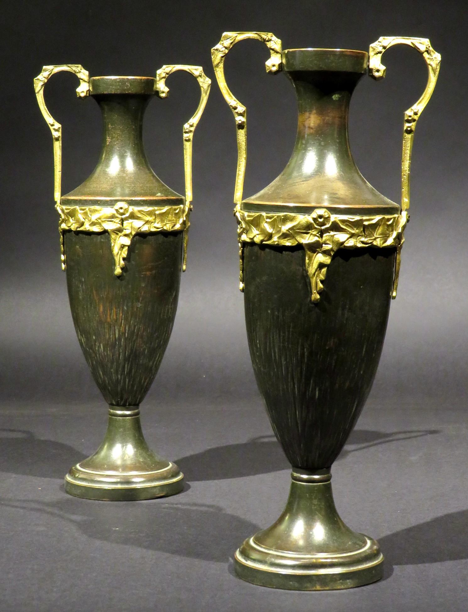 A very attractive pair of bronze patinated copper urns in the Neoclassical taste. 
Both ovoid shaped bodies showing embossed organic linear motifs, rising up to ormolu mounts & kylix handles, raised overall upon stepped circular bases. Unmarked but