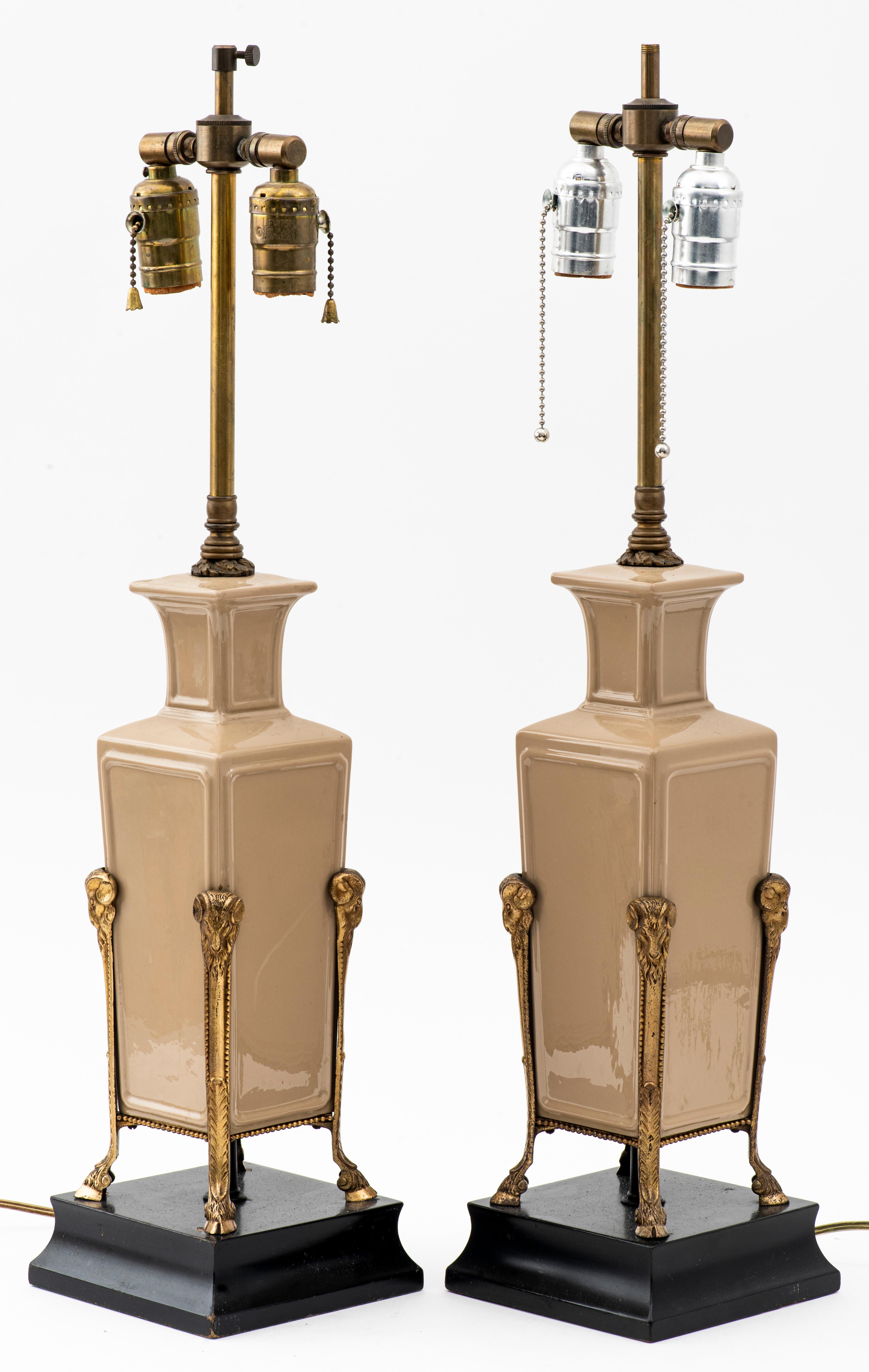 Neoclassical Revival pair of table lamps with beige ceramic vases mounted on metal stand with ibex heads and hoofed feet, mounted on ebonized square bases. Measures: 25.5