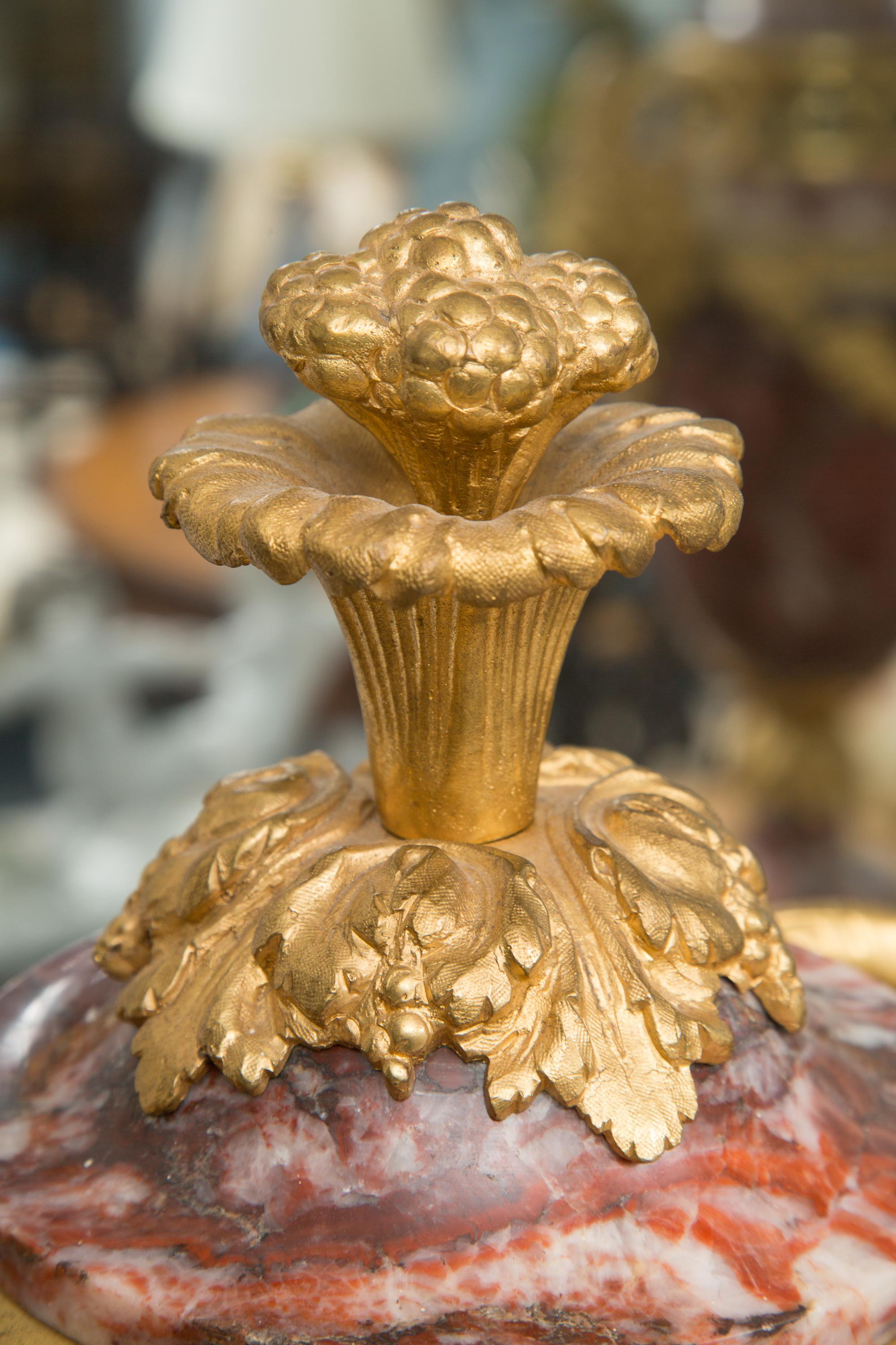 This is a stunning pair of rouge marble urns fitted with gilt bronze mounts. These large urns are beautifully figured marble, decorated with bronze castings of floral swags and ram’s head figural handles. Each urn is situated on a similar base,