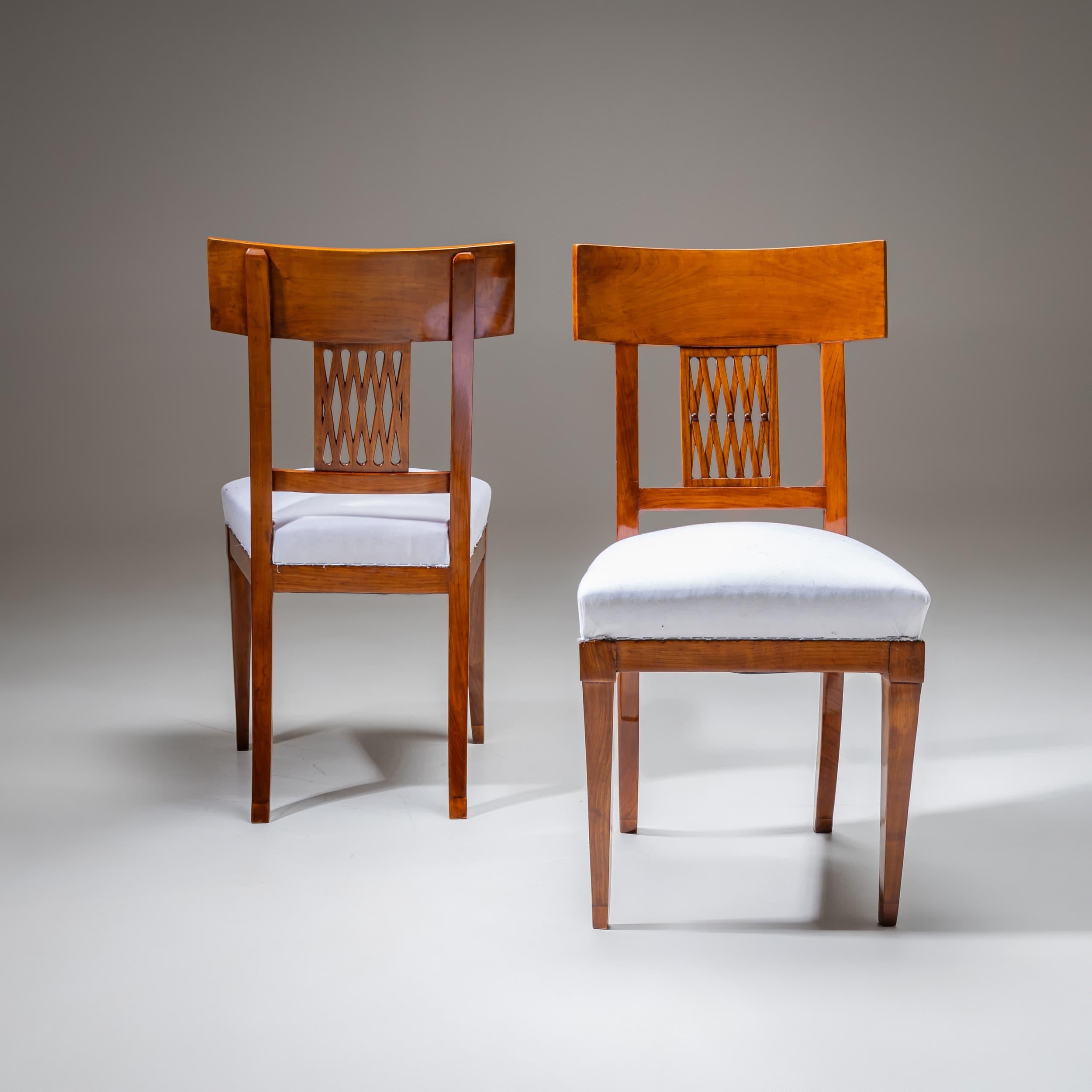Paire de chaises néoclassiques en merisier, fabriquées vers 1800. Les chaises présentent des dossiers élégamment percés avec une délicate structure en treillis dans l'éclisse centrale. Ils reposent sur des pattes avant effilées, avec des épaules