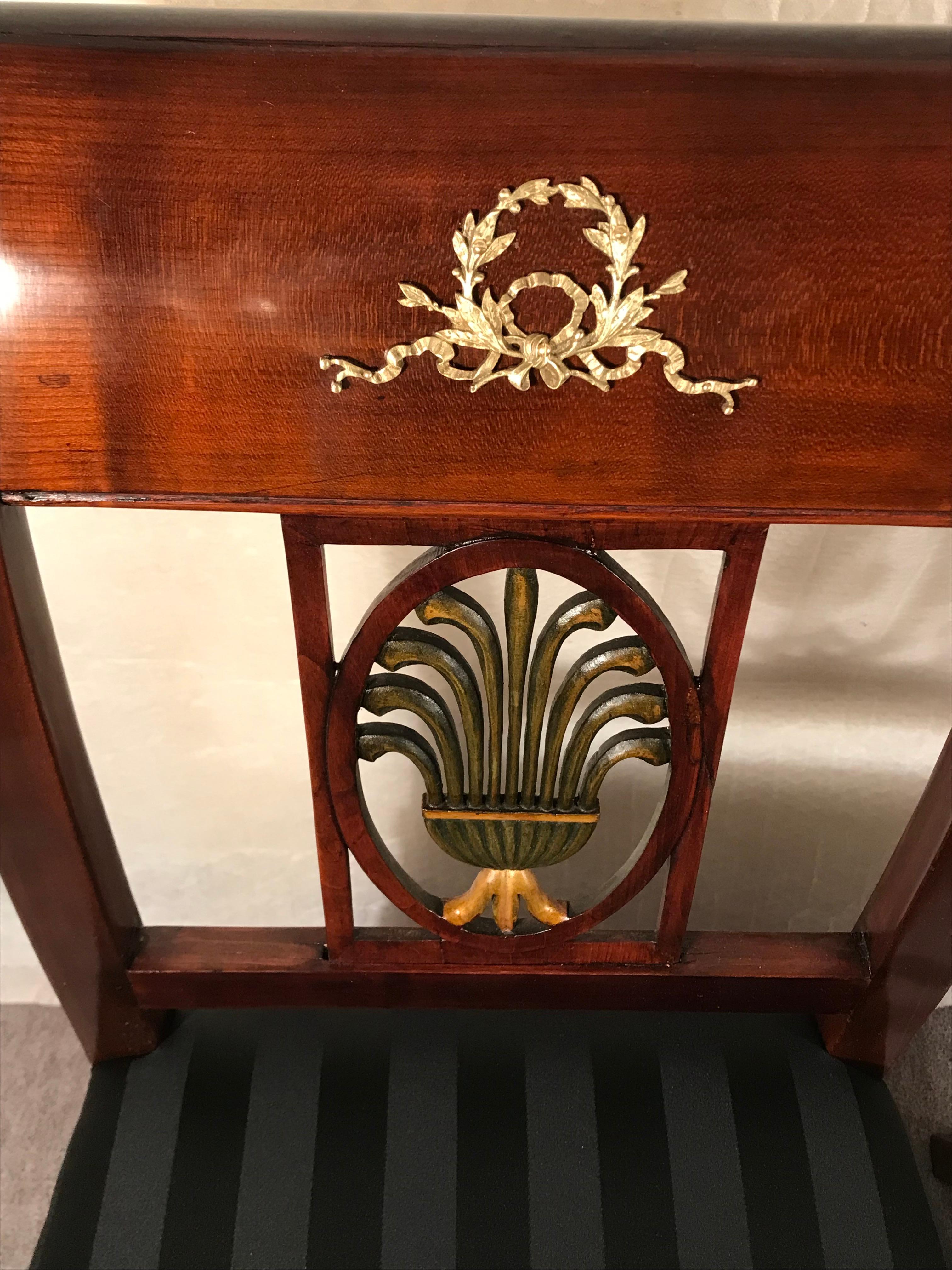 This pair of Neoclassical chairs dates back to the beginning of the 19th century. They have a very pretty backrest, with an open work decor. Additionally, they are embellished with matching brass fittings. The chairs have been professionally
