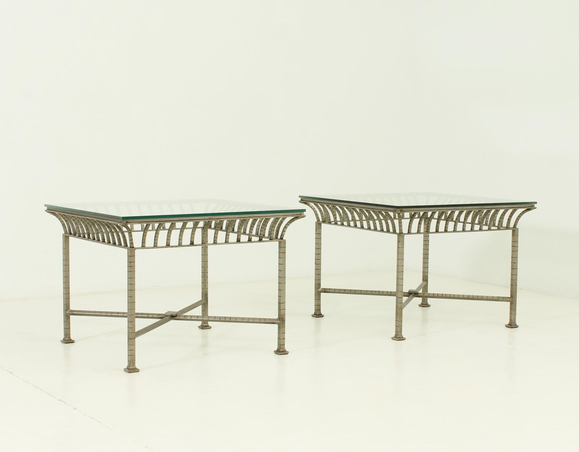 Pair of neoclassical side tables from 1960's in the manner of Maison Charles, France. Polished metal and clear glass table top.