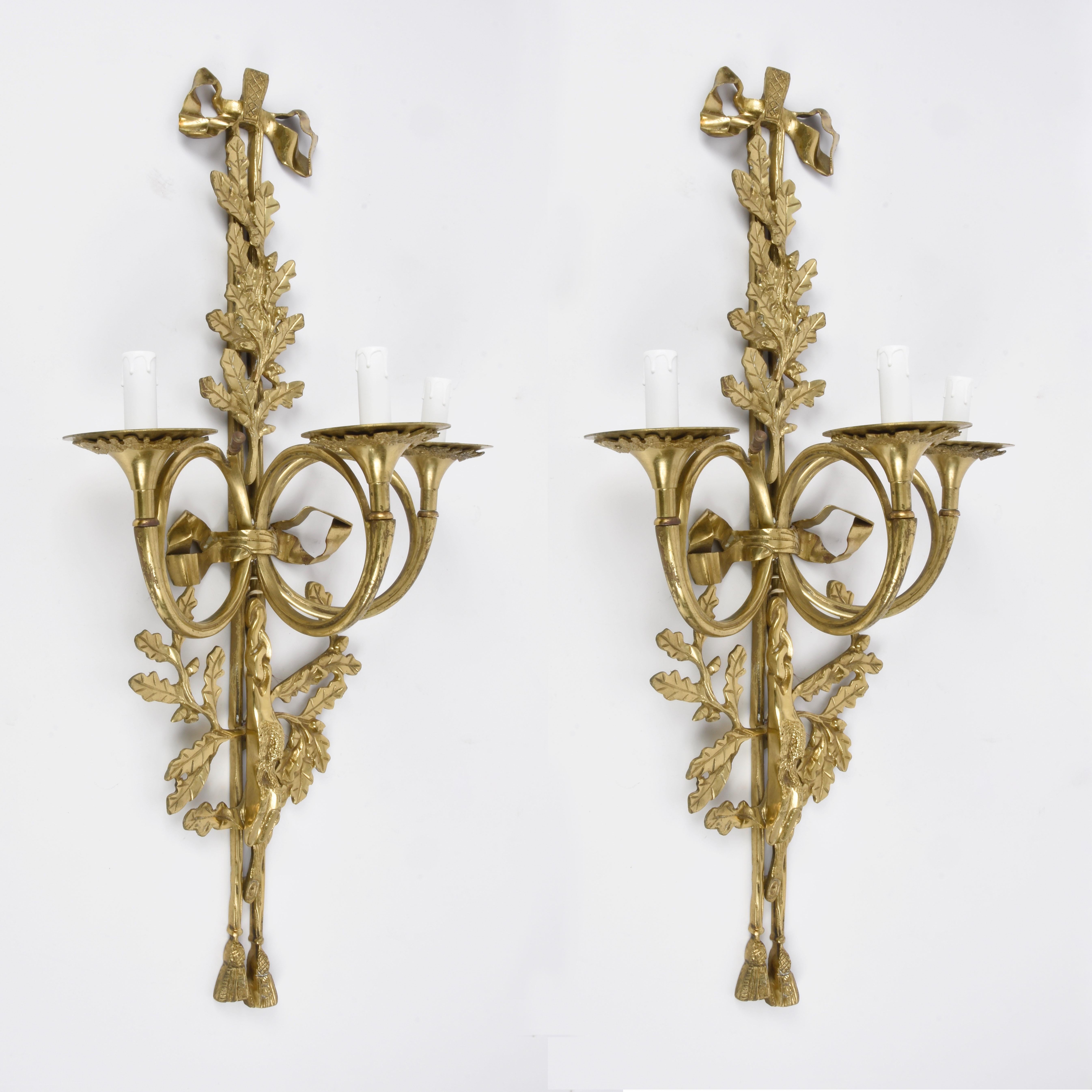 Amazing large pair of neoclassical brass and bronze sconce with three arms and trumpet-shaped wall sconces. This wonderful piece was produced in France in 1930s.

This pair of lights is finely cast with rope and tassels, bows, twigs, oak leaves