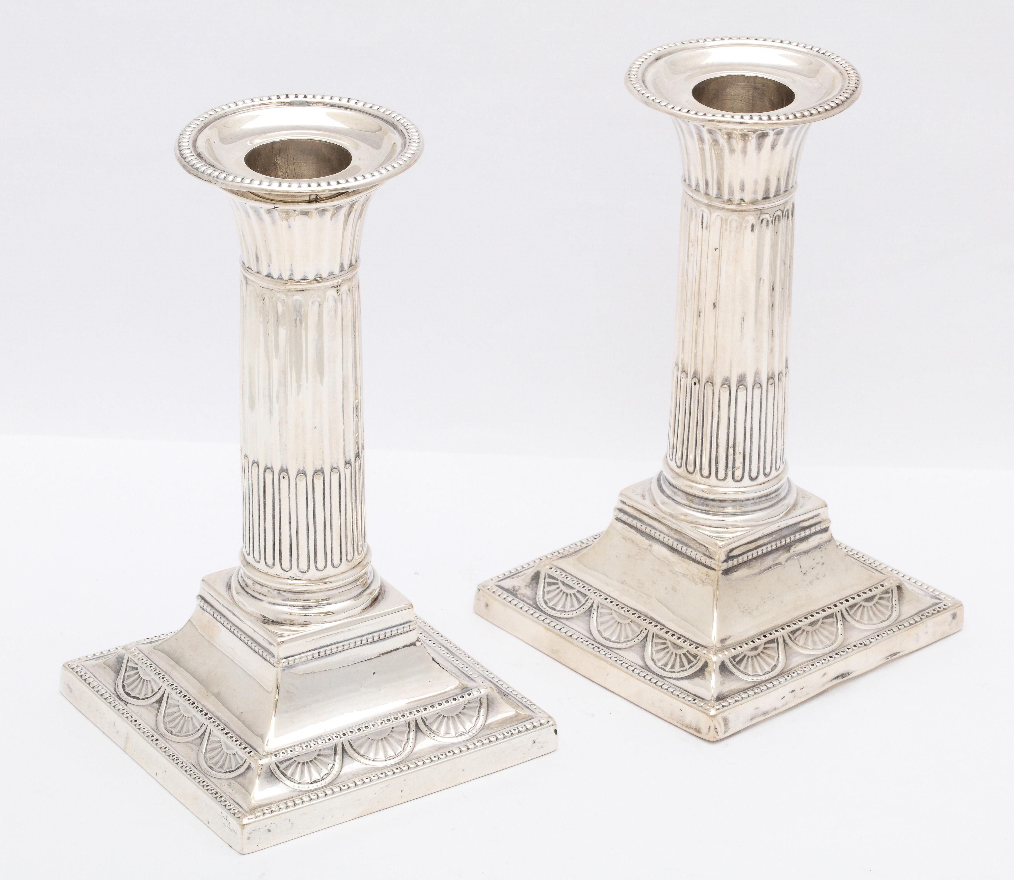 Pair of sterling silver, neoclassical, column-form candlesticks, London, year-hallmarked for 1895, William Hutton and Sons - makers. Each candlestick measures: 5 1/2 inches high x 3 1/2 inches deep (across square base) x 3 1/2 inches wide (across
