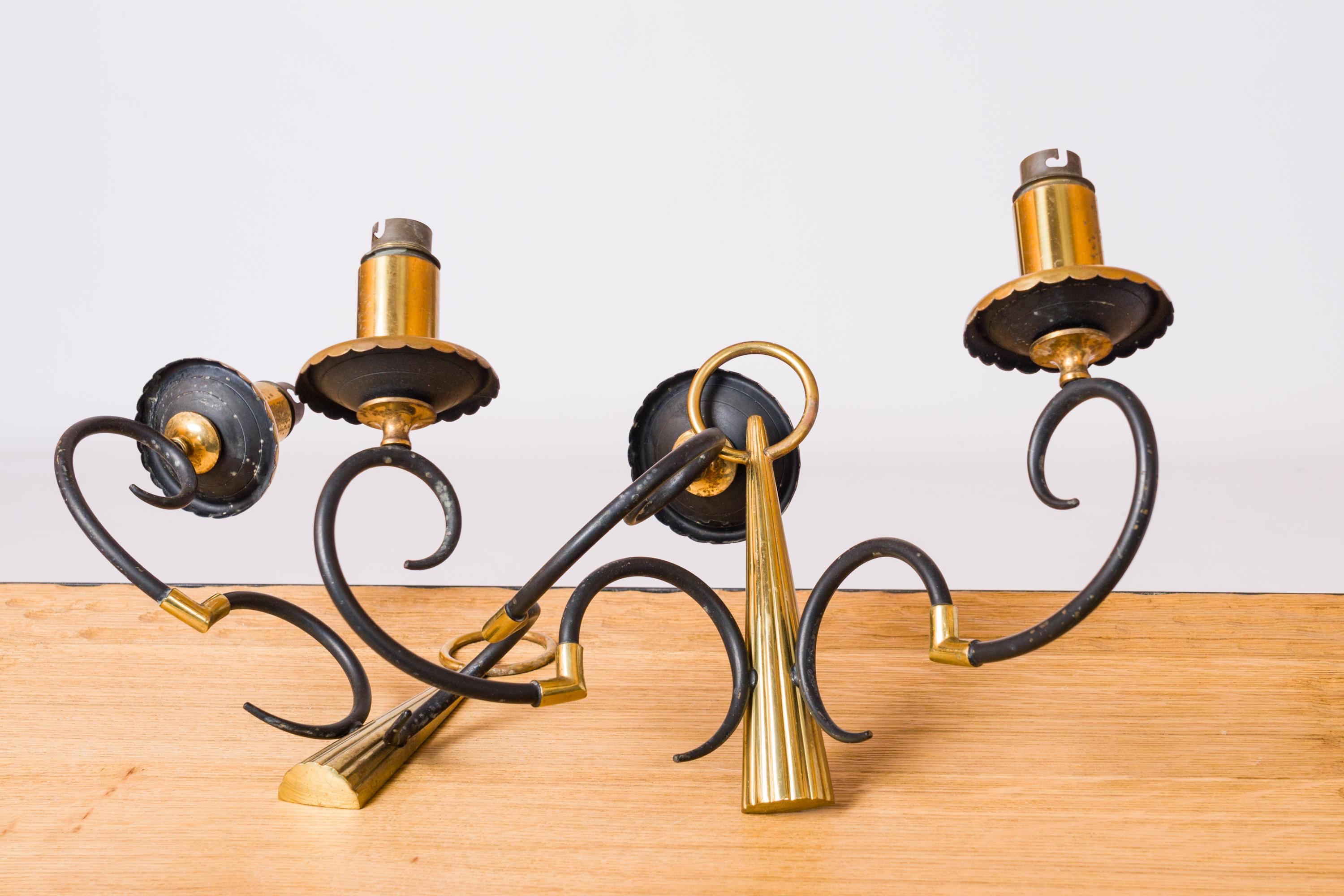 Una coppia di applique in stile neoclassico realizzate negli anni '60 da Maison Arlus, un'azienda francese di illuminazione. Due bracci luminosi a forma di doppio gancio rovesciato uniti da un pezzo di metallo dorato. Si estendono da un gambo
