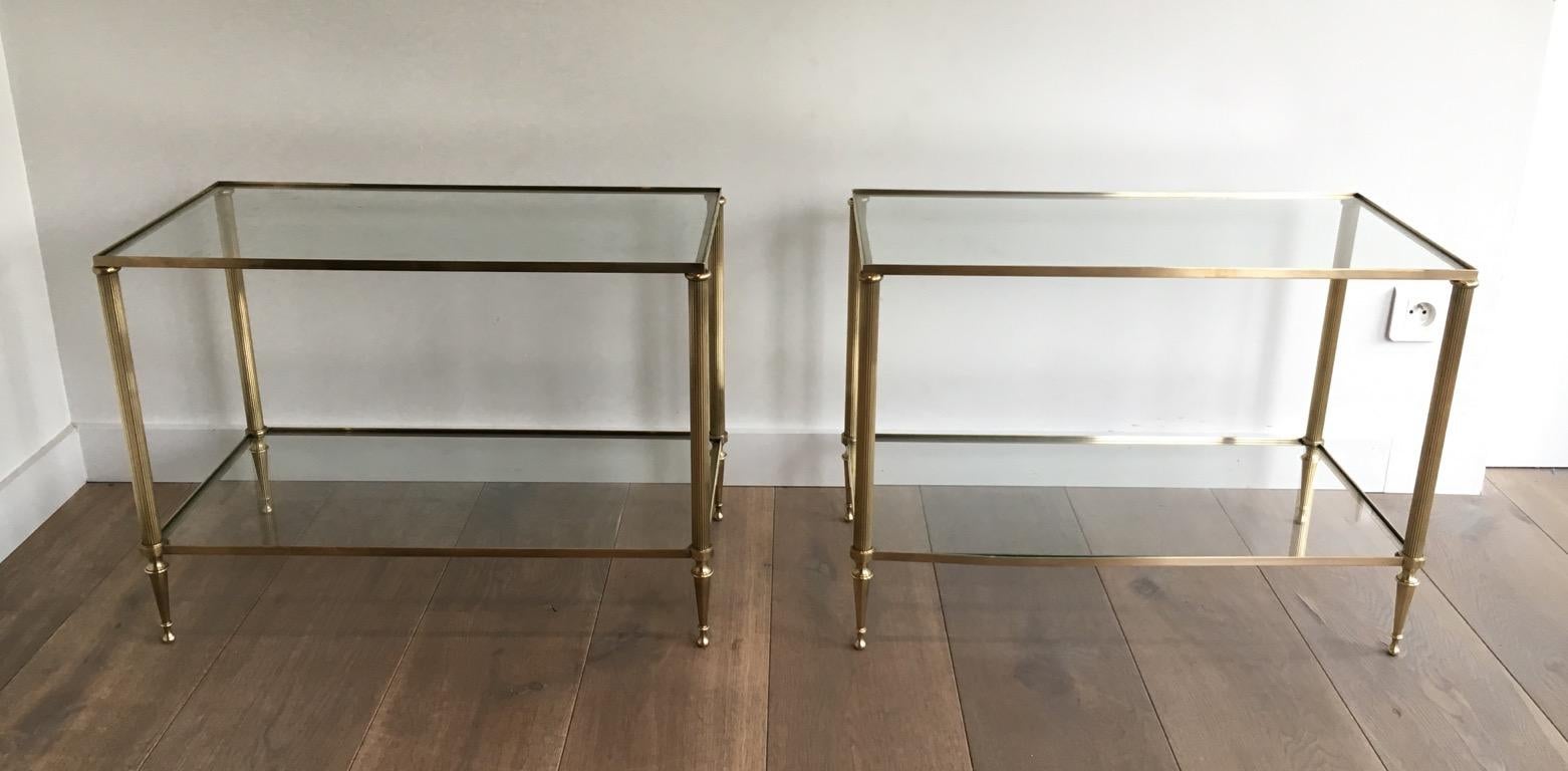 This very nice and elegant pair of neoclassical style side tables is made of brass with fluted legs and glass shelves. This is a French work attributed to Maison Jansen. Circa 1940