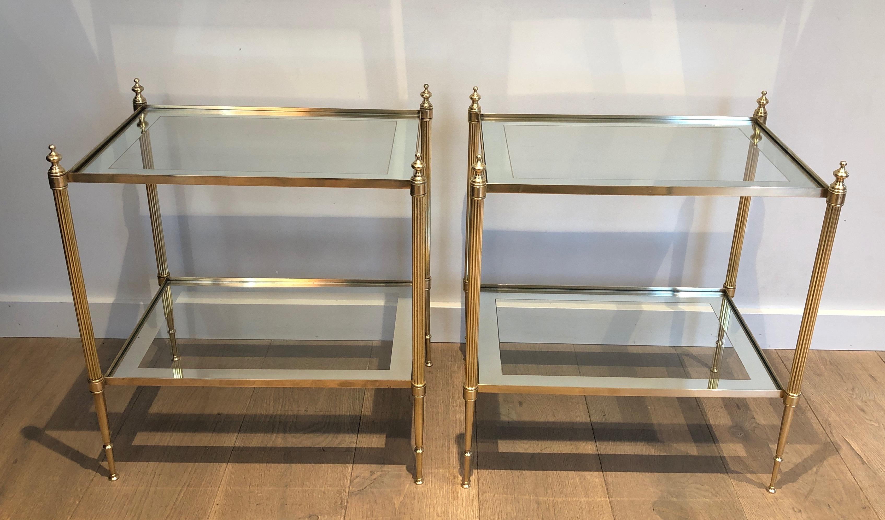 This very nice and elegant pair of neoclassical style side tables is made of  brass with fluted legs and glass shelves surrounded by a silvered mirror line. This is a French work by Maison Jansen. Circa 1940
