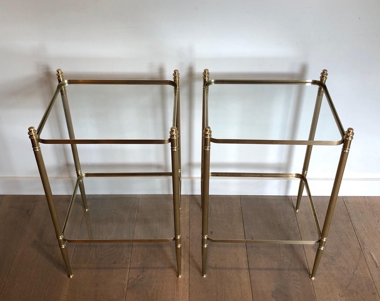 This pair of neoclassical style side tables are made of brass with fluted legs and rounded corners. They have 2 glass shelves. This is a French work in the style of famous Maison Jansen, circa 1940.