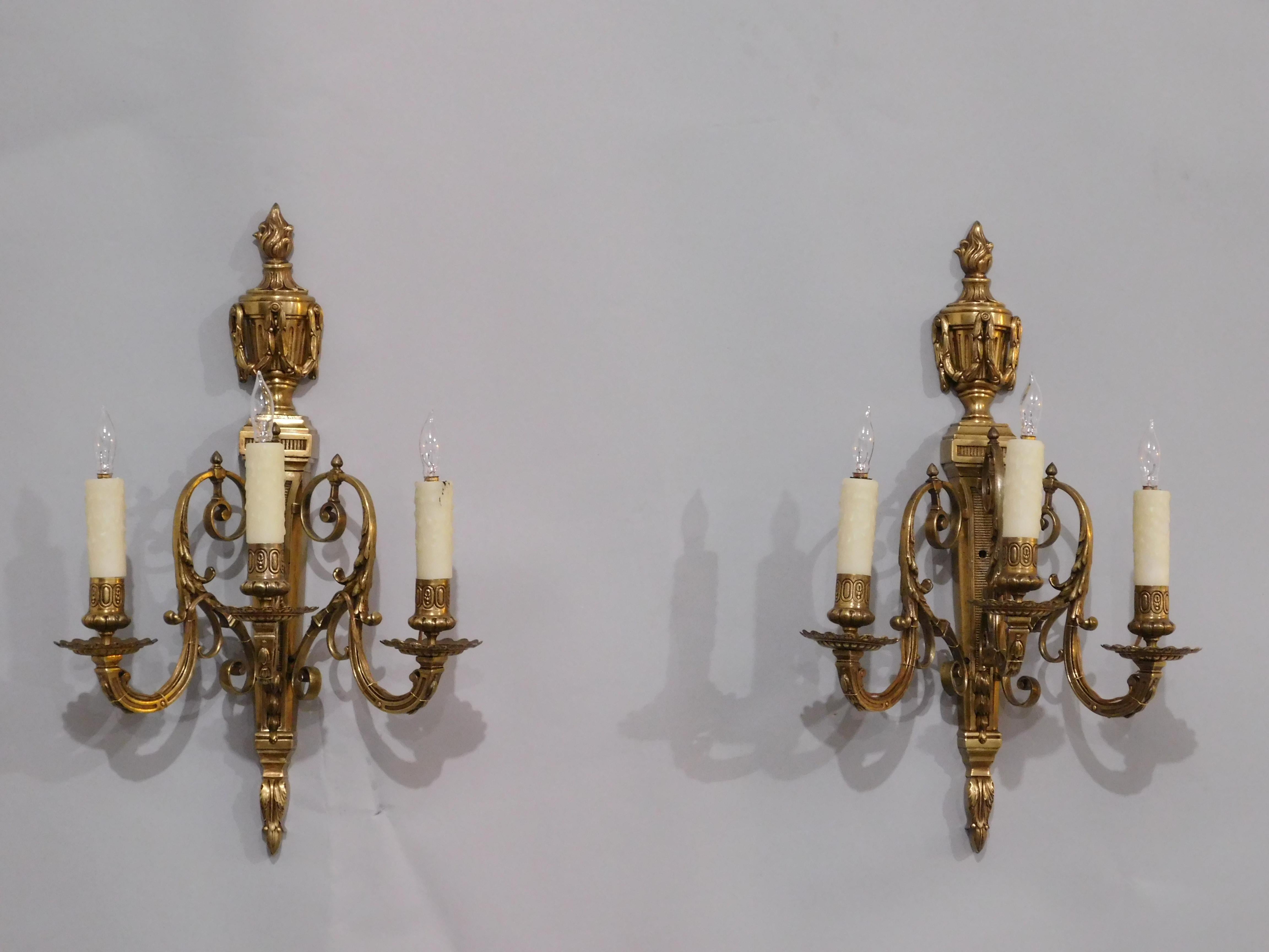 Pair of French Neoclassical Cast Brass 3-Light Wall Sconces.  Luminaire bracket shaped shaft with horizontal ribbed design issuing three s-shaped branches cascading foliage sprouting a detailed bobeche and candle holder, crowned with a Louis XVI