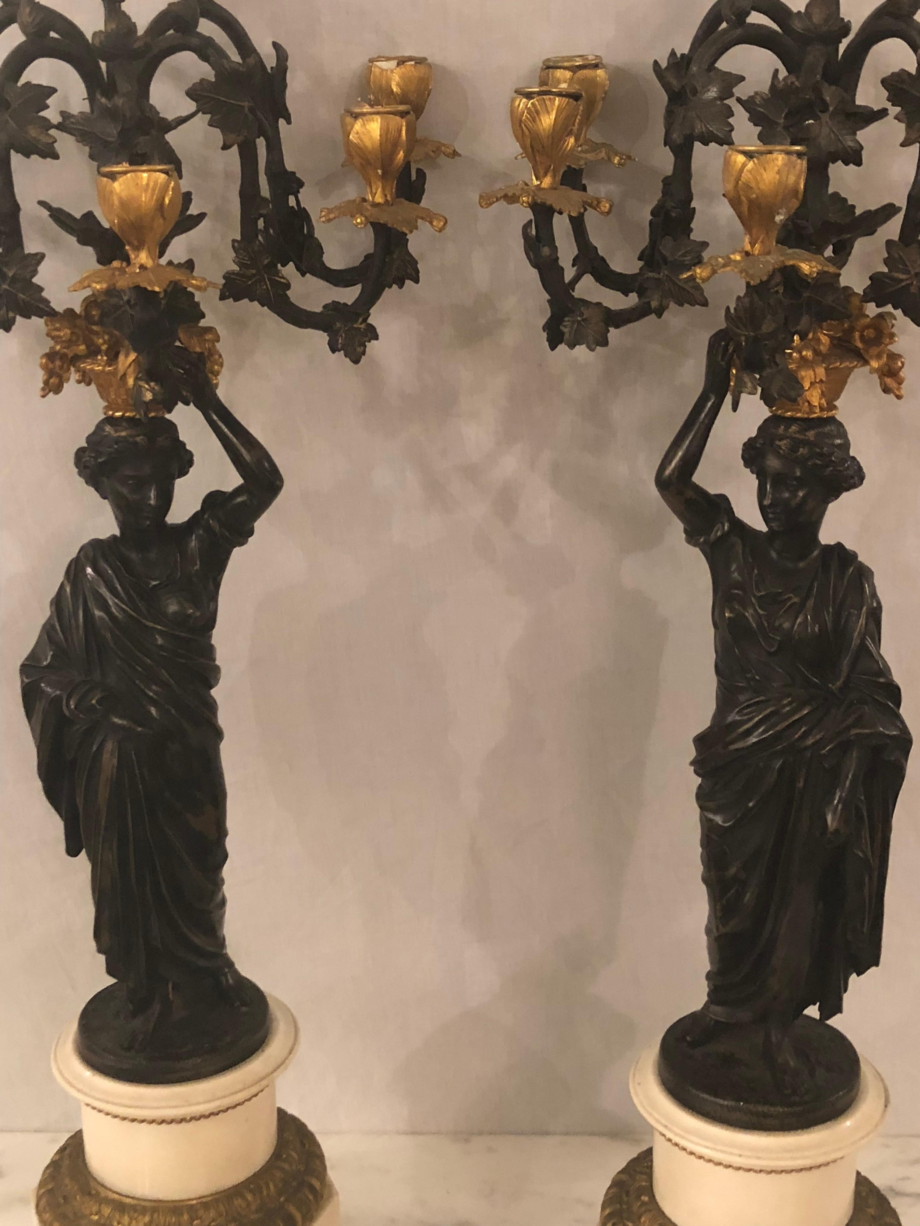 Pair of neoclassical style bronze six-arm figural candelabra. Each depicting a maiden in Greek garments serving a basket of fruit a top their heads done in patinated and doré bronze with pedestal bases. 

 