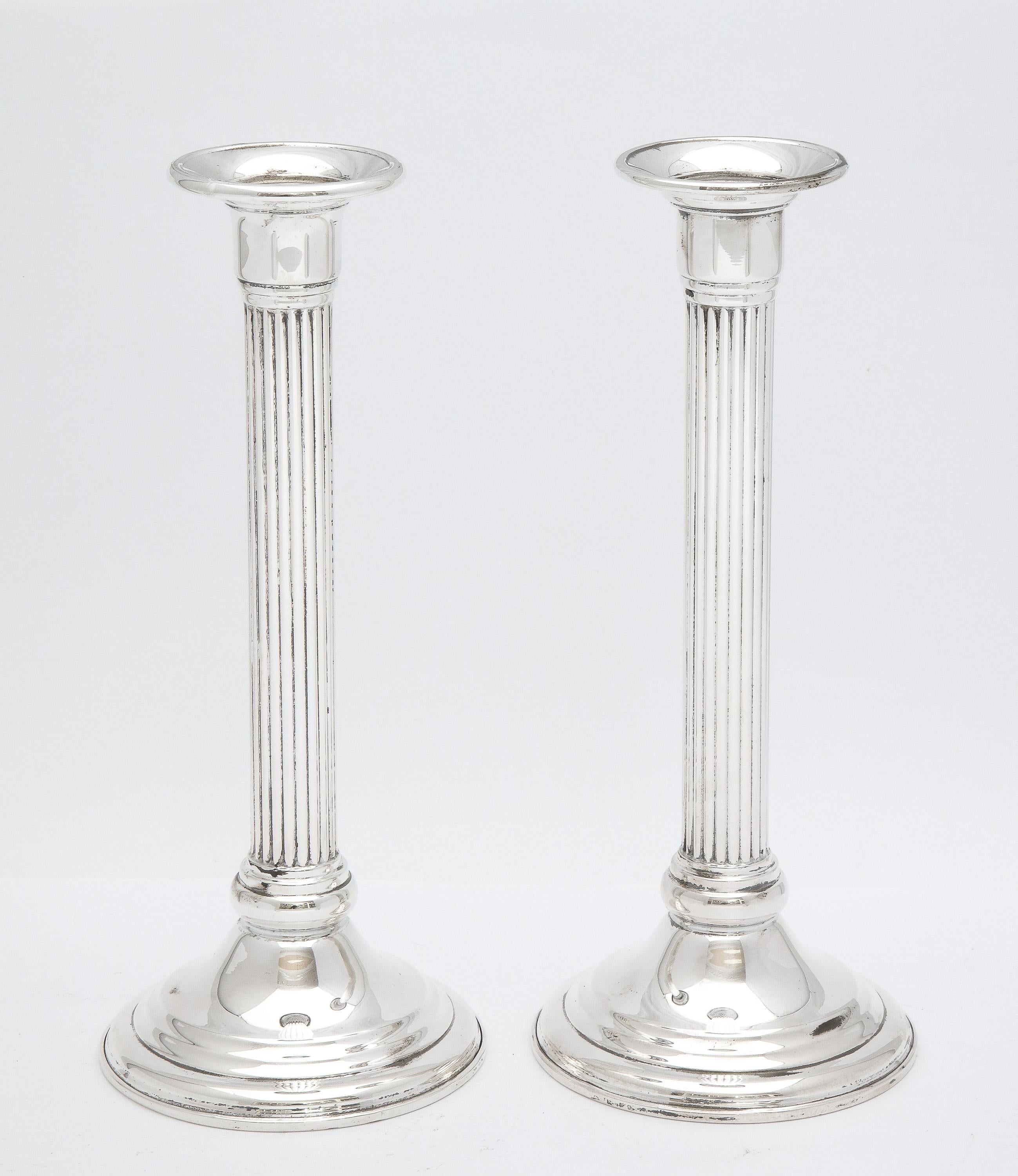 Pair of sterling silver, Neoclassical-style candlesticks, American, Ca, 1950's. Each candlestick measures 8 1/4 inches high x 3 1/2 inches diameter across base. Weighted. Dark areas on sterling silver in photos are reflections. In excellent vintage