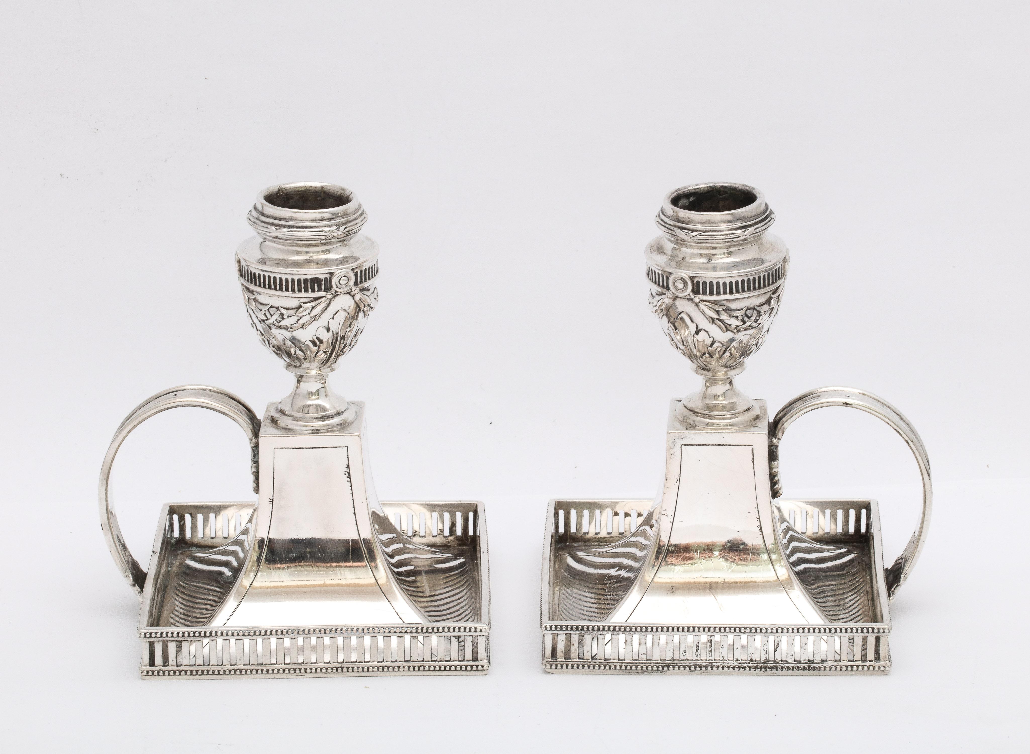 Pair of Neoclassical-style, Continental Silver (.800) chambersticks, Germany, Ca. 1910. Each chamberstick measures 5 inches high x 3 3/4 inches deep x 3 3/4 inches wide x 4 inches from outer edge of handle to outer edge of base. Pierced gallery on