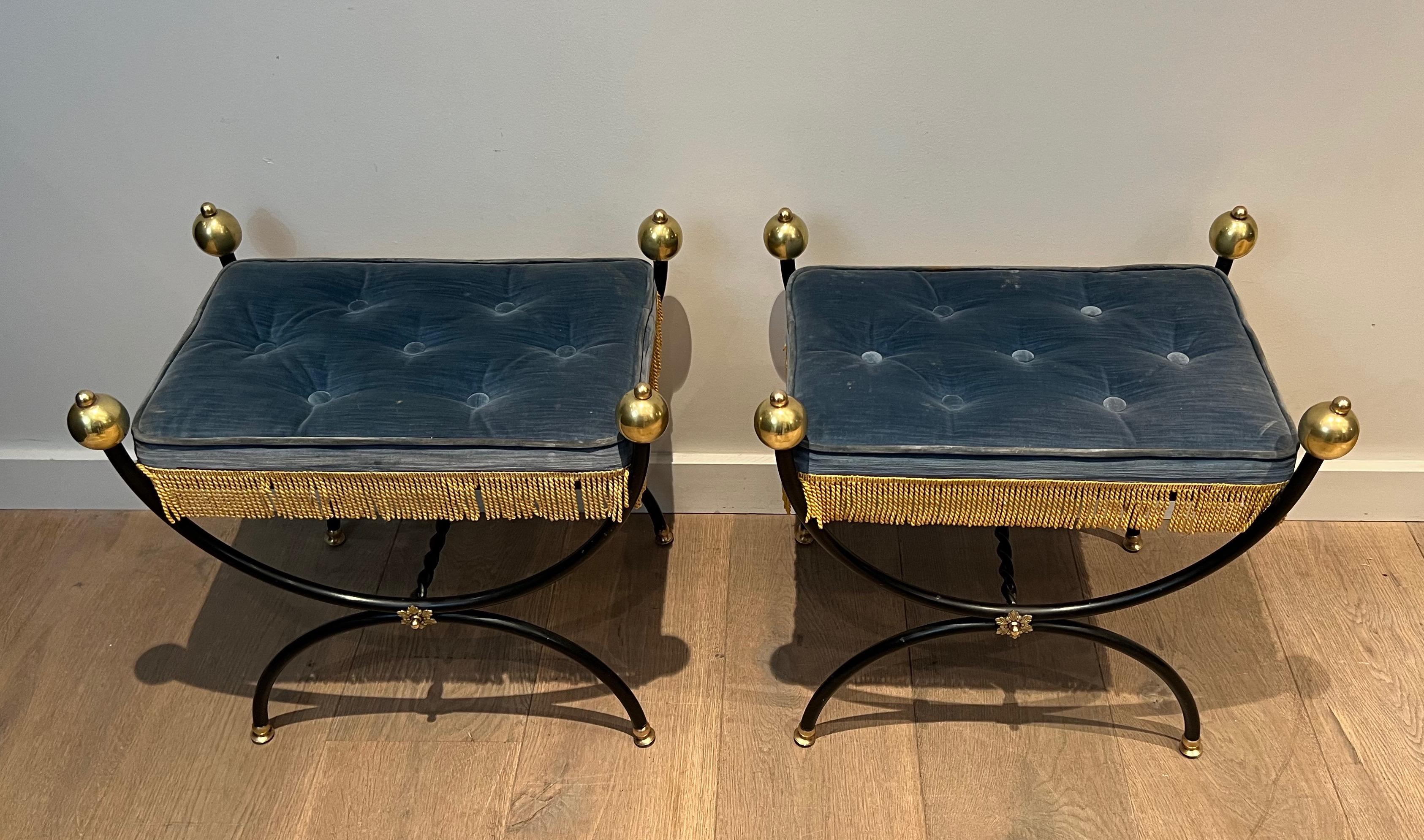 This very elegant pair of neoclassical style curule stools is made of a black lacquered metal base topped with large brass balls. The seats are covered with a Royal blue velvet and golden fringes. This is a French work. Circa 1950