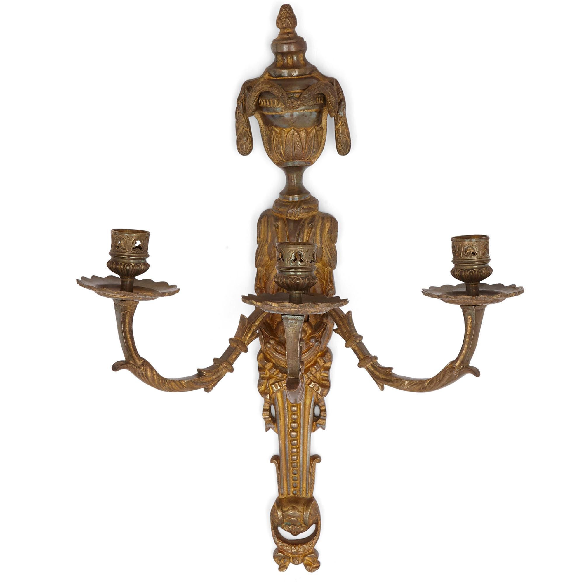 Pair of neoclassical style gilt bronze sconces
French, 19th century
Measures: Height 46cm, width 33cm, depth 23cm

This pair of gilt bronze scones is a fine example of the Louis XVI style. Each scone supports three light branches, each branch