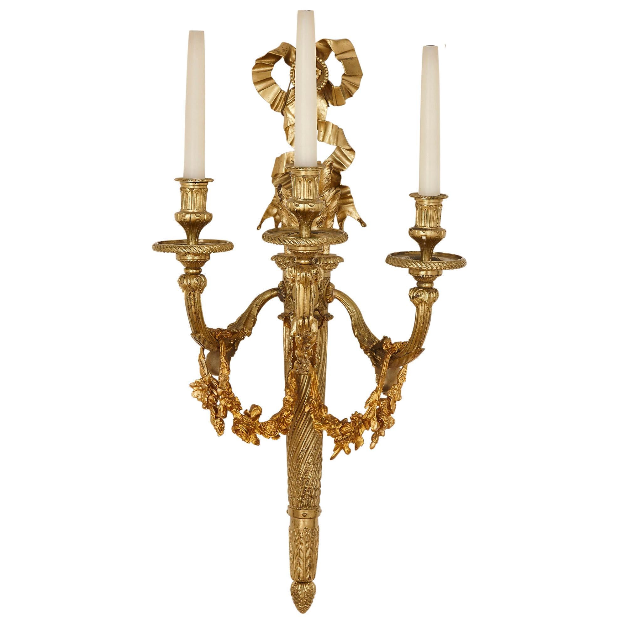 Pair of neoclassical style gilt bronze three-light sconces
French, 19th century
Measures: Height 75cm, width 37cm, depth 30cm

The sconces in this pair are after a famous model by Pierre-François Feuchère, one of the leading craftsmen of the