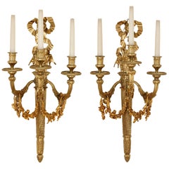 Zwei dreiflammige Wandleuchter aus vergoldeter Bronze im neoklassischen Stil