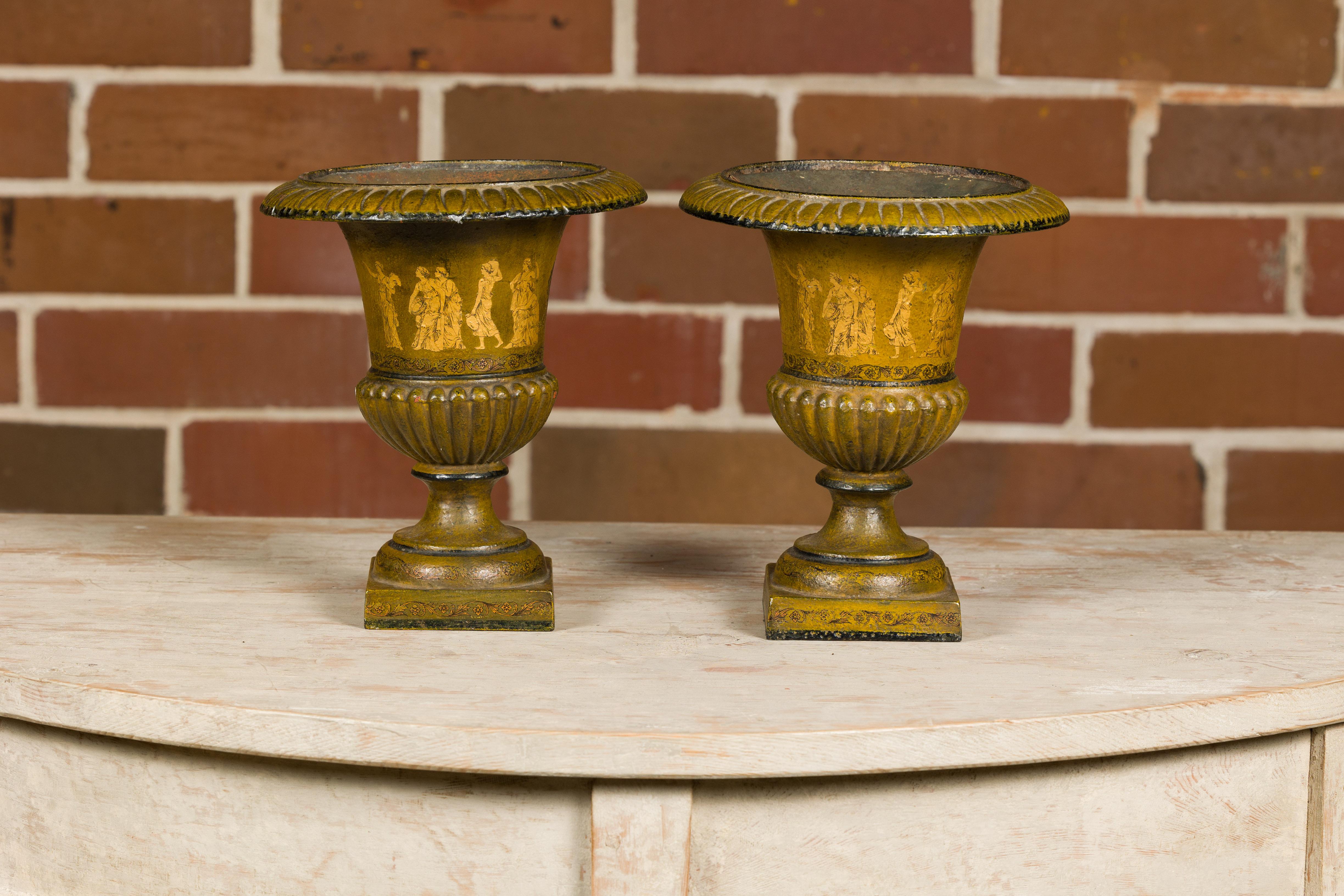 A pair of Neoclassical style iron urn planters from circa 1900 with liners and mythological figures. This pair of Neoclassical-style iron urn planters from circa 1900 embodies the grandeur and elegance of a bygone era. Each planter is a masterful