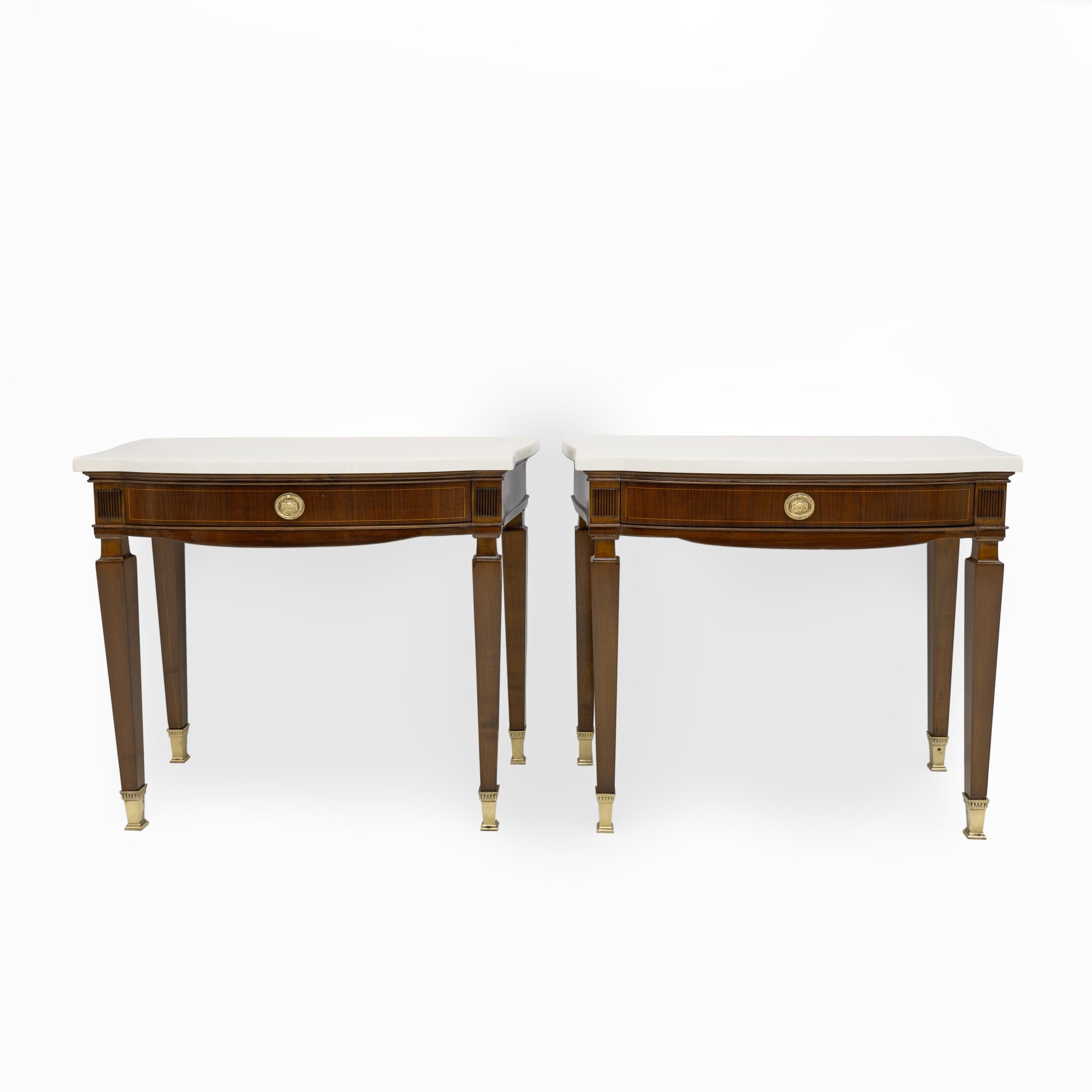 Pair of mahogany bedside tables, each of which has an ivory-coloured marble top, shaped sides equipped with original brass handles and feet. This pair of coffee tables has been restored and is ready for the home. c1950